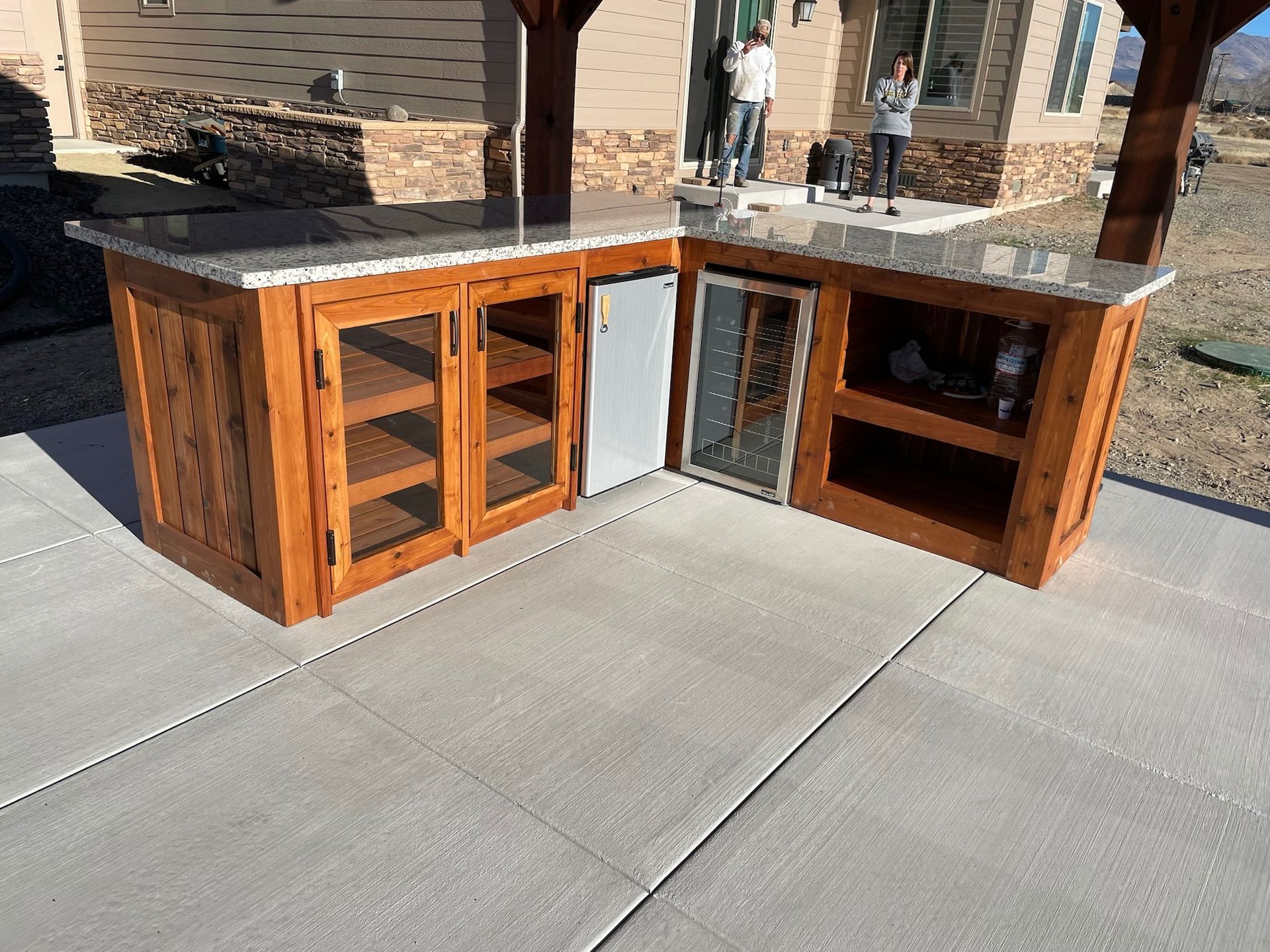 A large wooden cabinet with a marble counter top is sitting on a concrete patio.