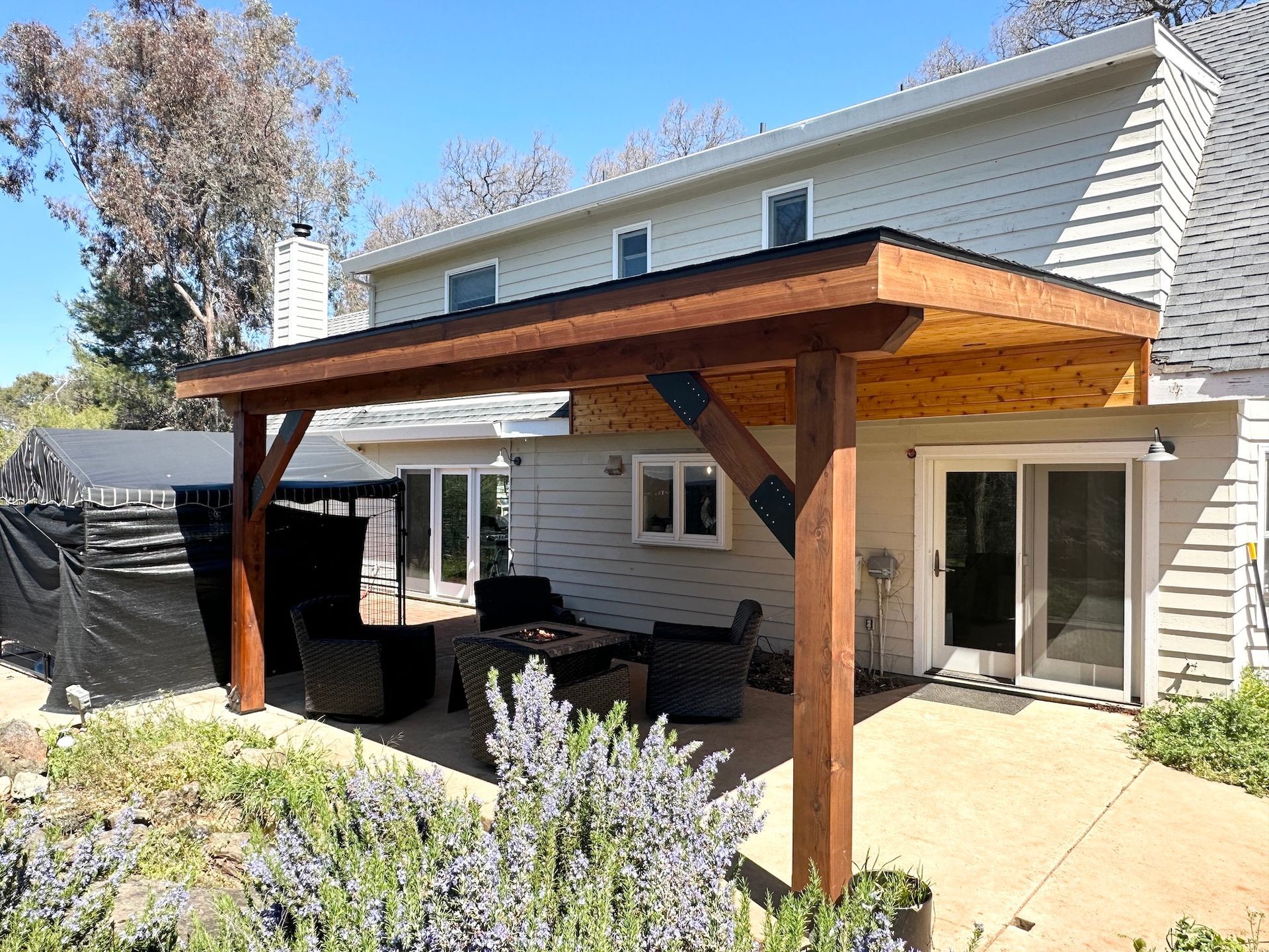 A white house with a wooden pergola in front of it