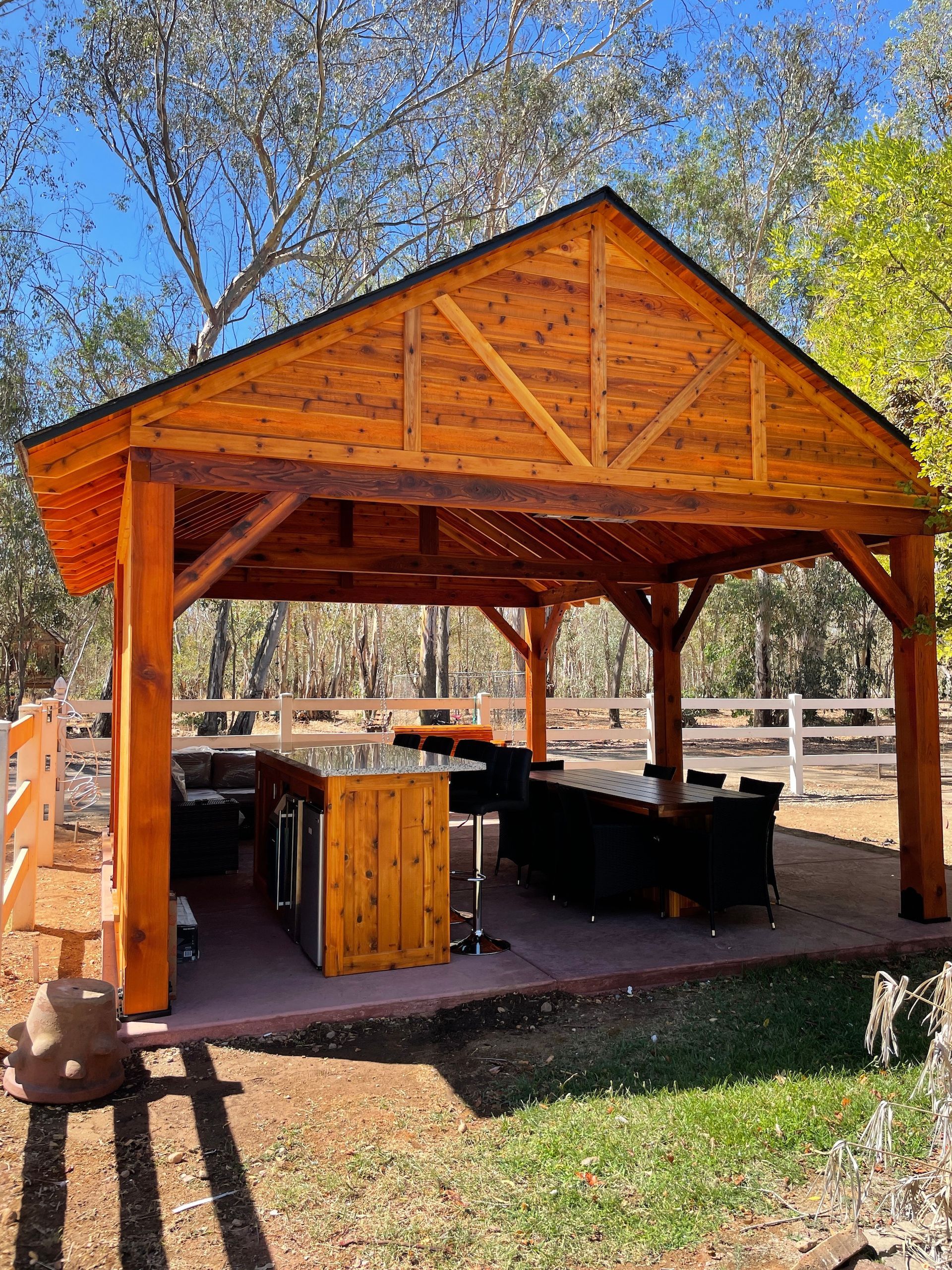 A wooden pavilion with a table and chairs underneath it