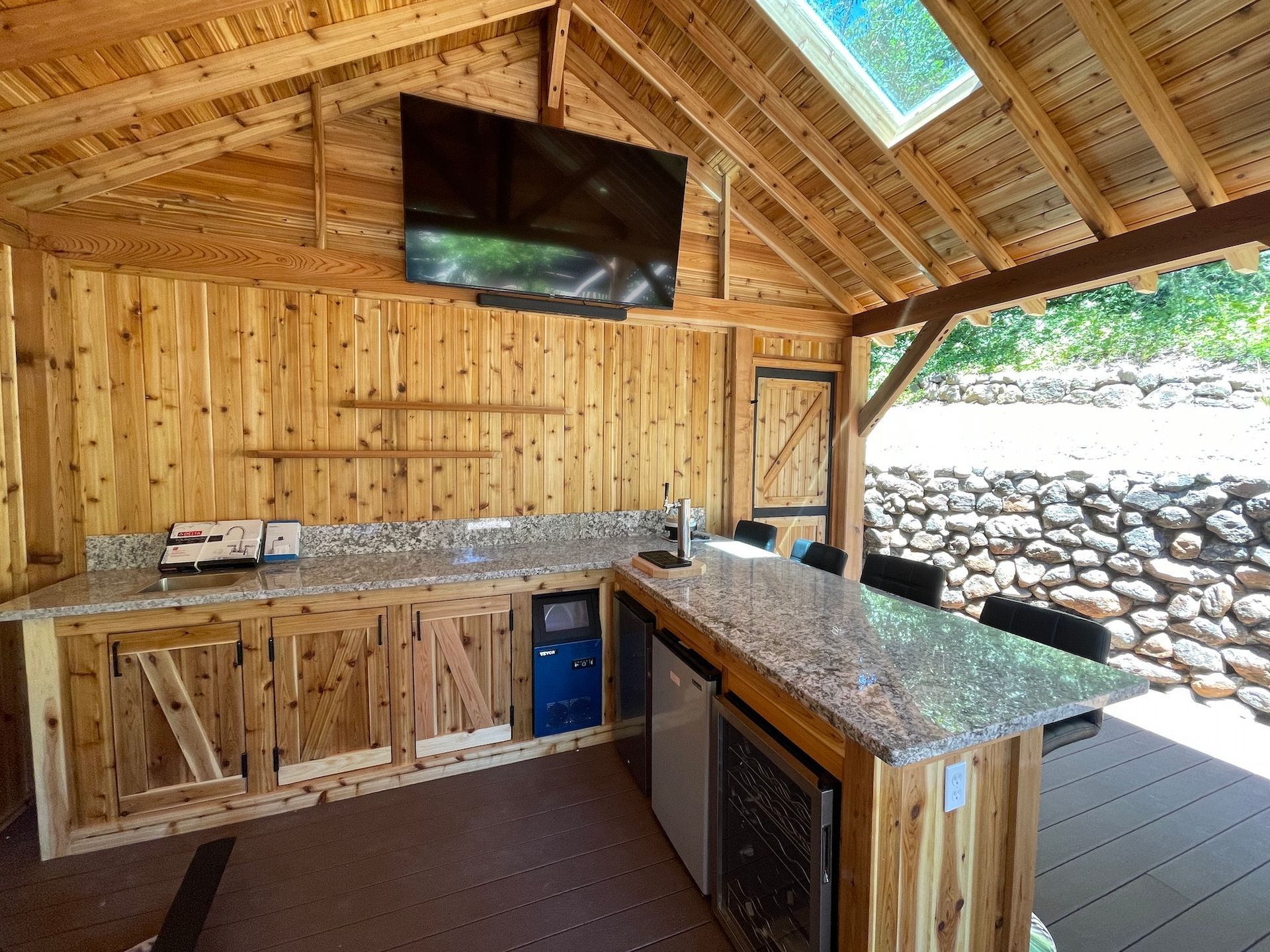 A kitchen with a large flat screen tv hanging from the ceiling.