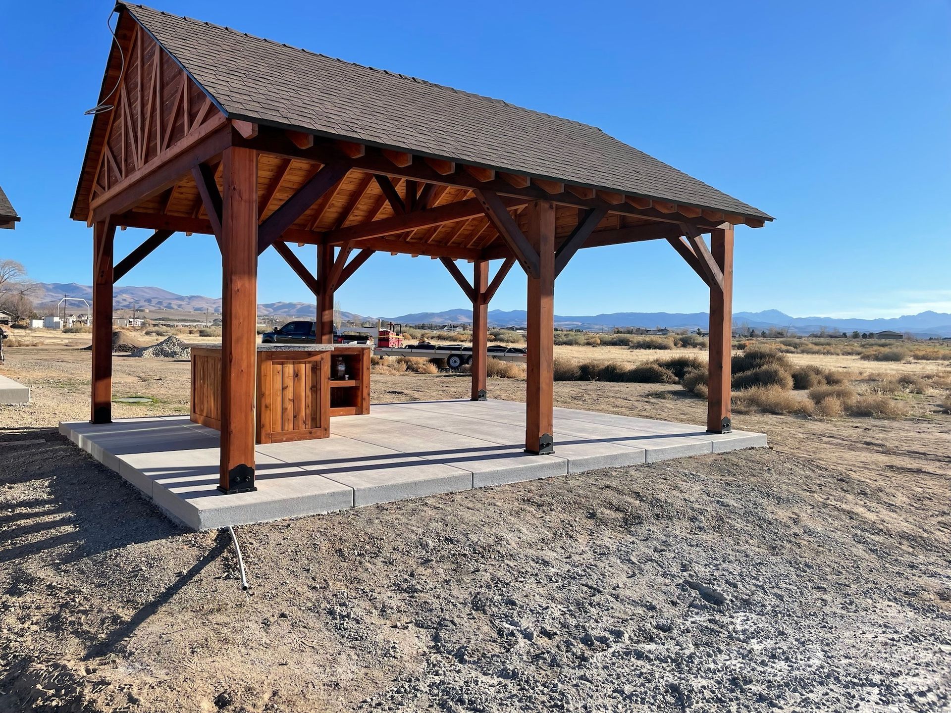 A wooden gazebo in the middle of a dirt field