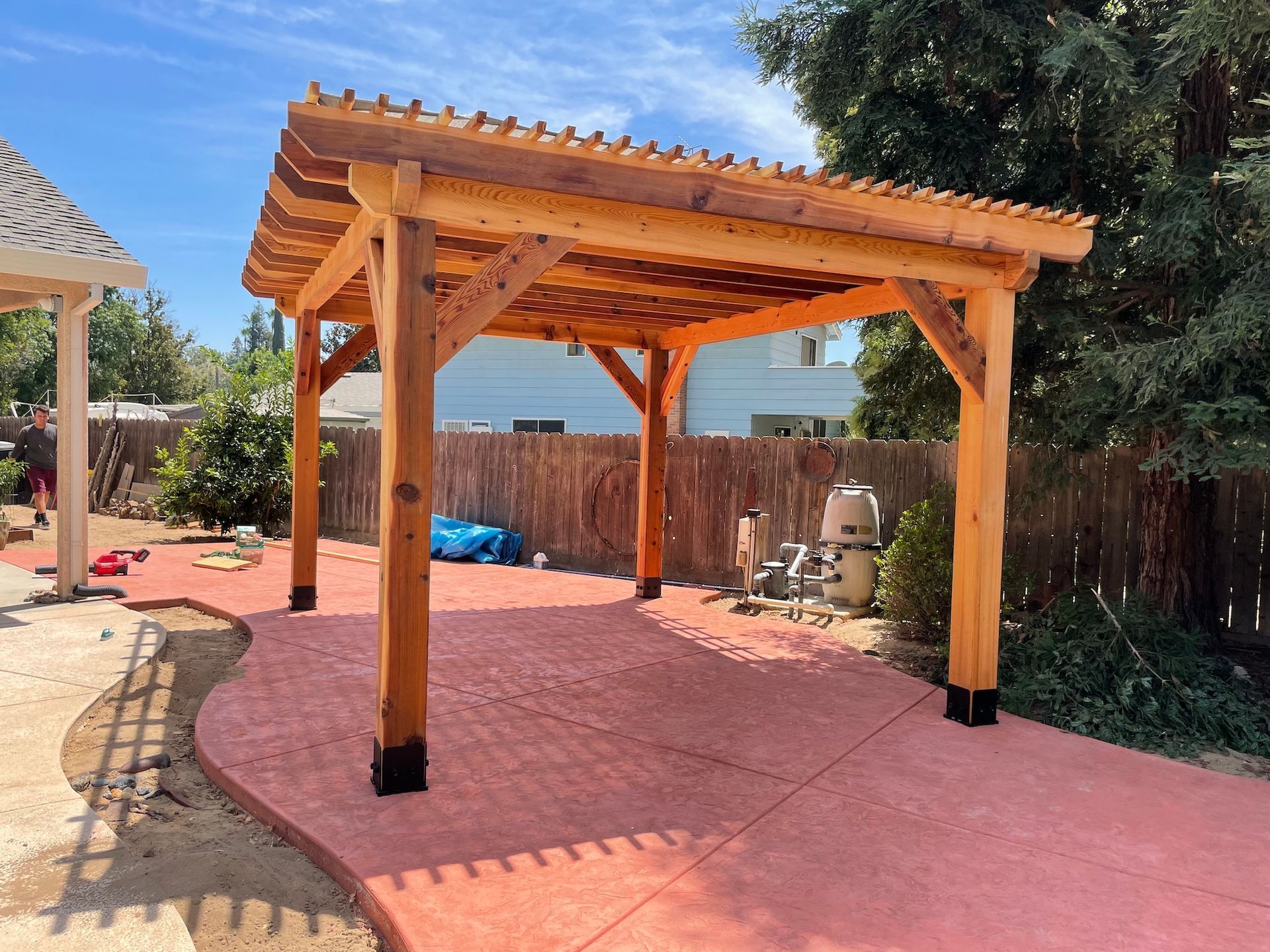 A wooden pergola is sitting on top of a concrete patio.