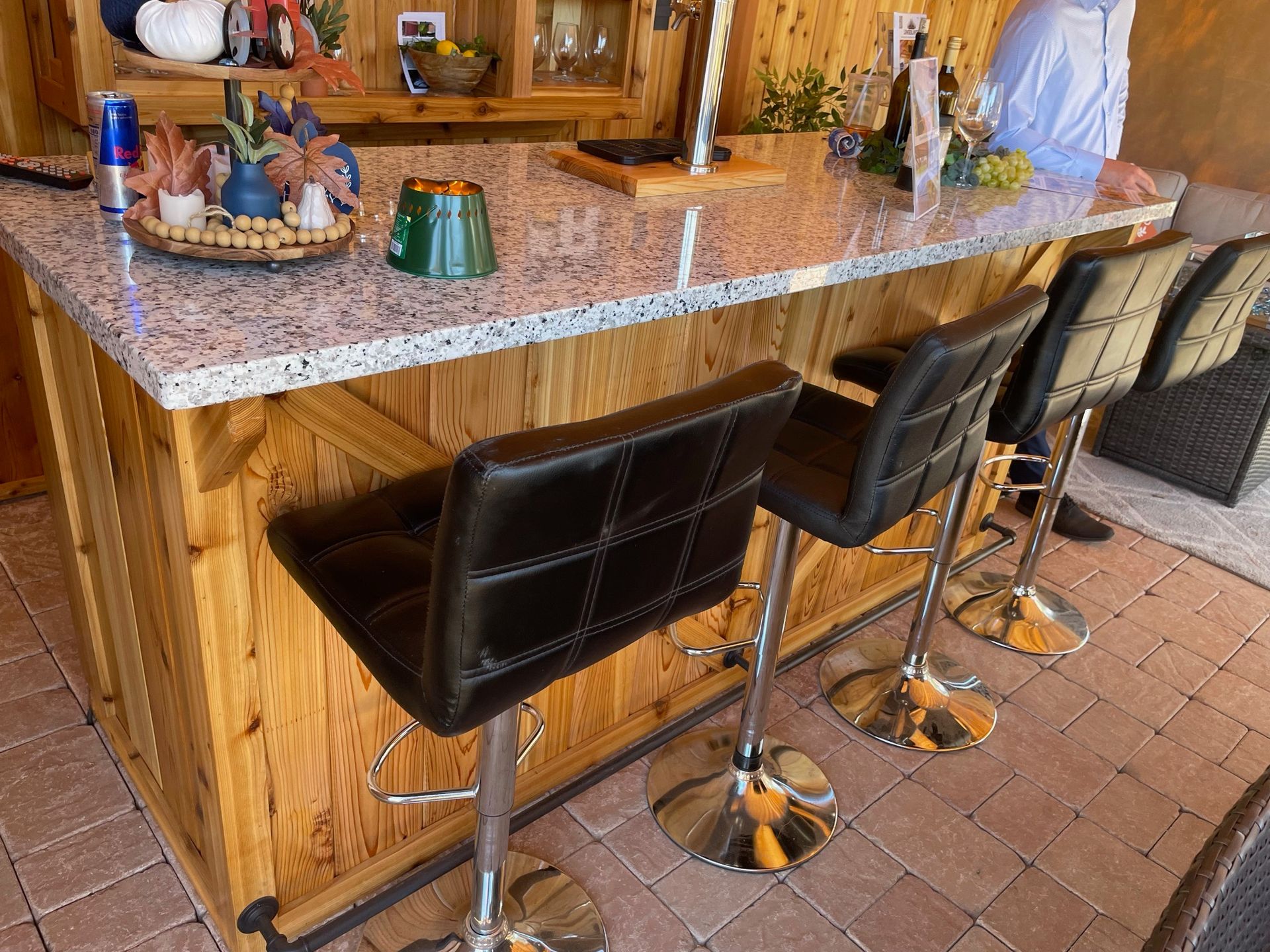 A wooden bar with a granite counter top and black bar stools