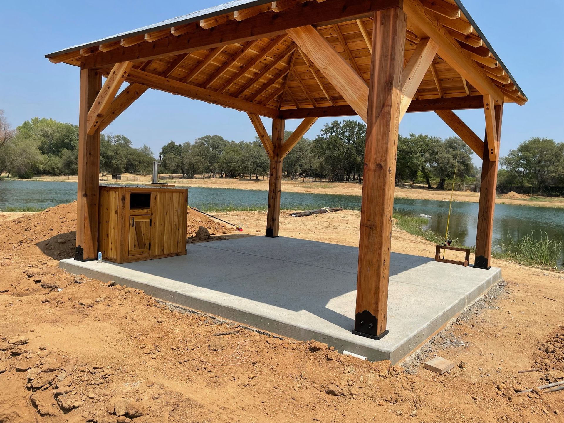 A wooden pavilion is sitting next to a lake.