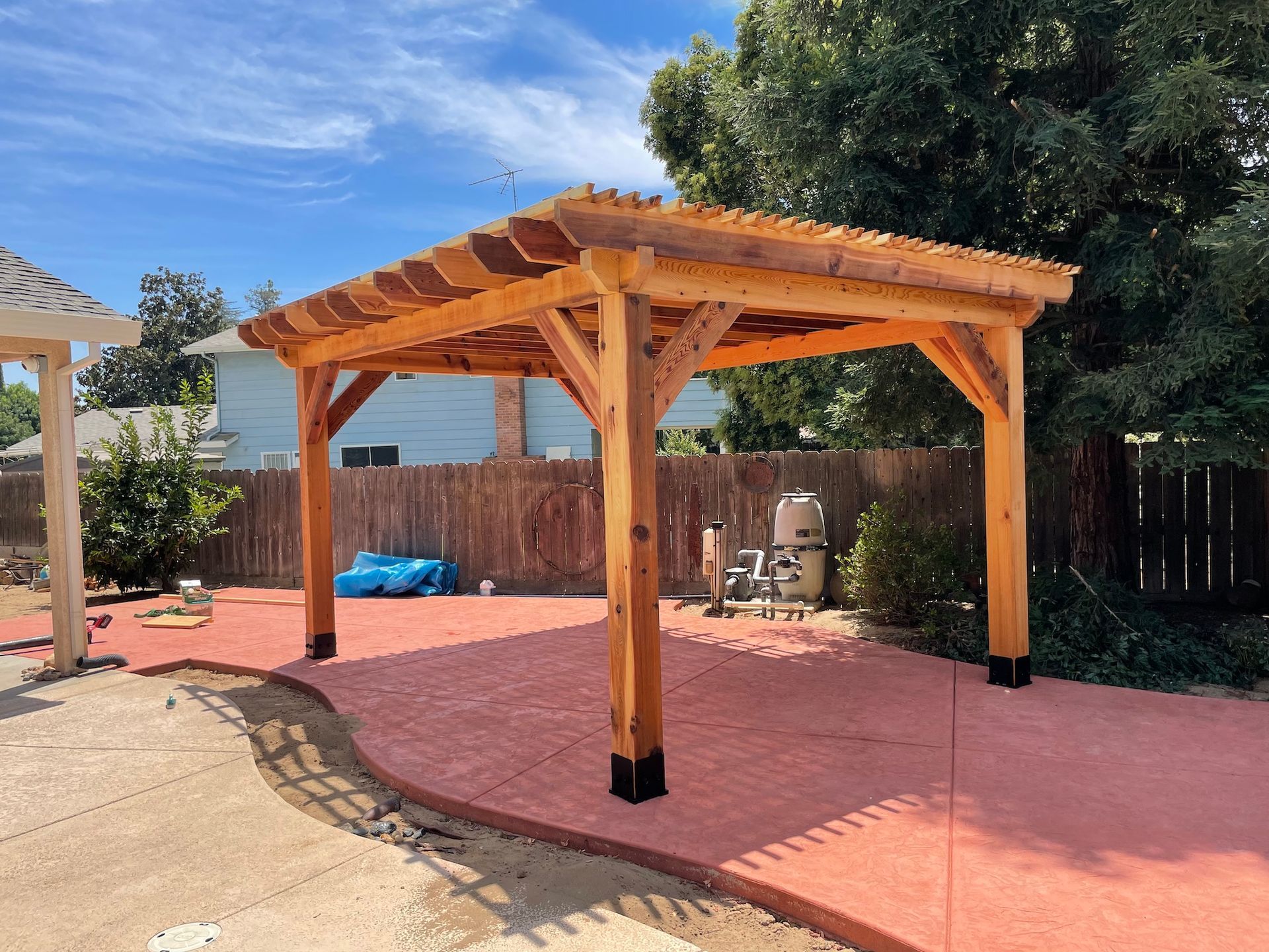 A wooden pergola is sitting on top of a concrete patio in a backyard.