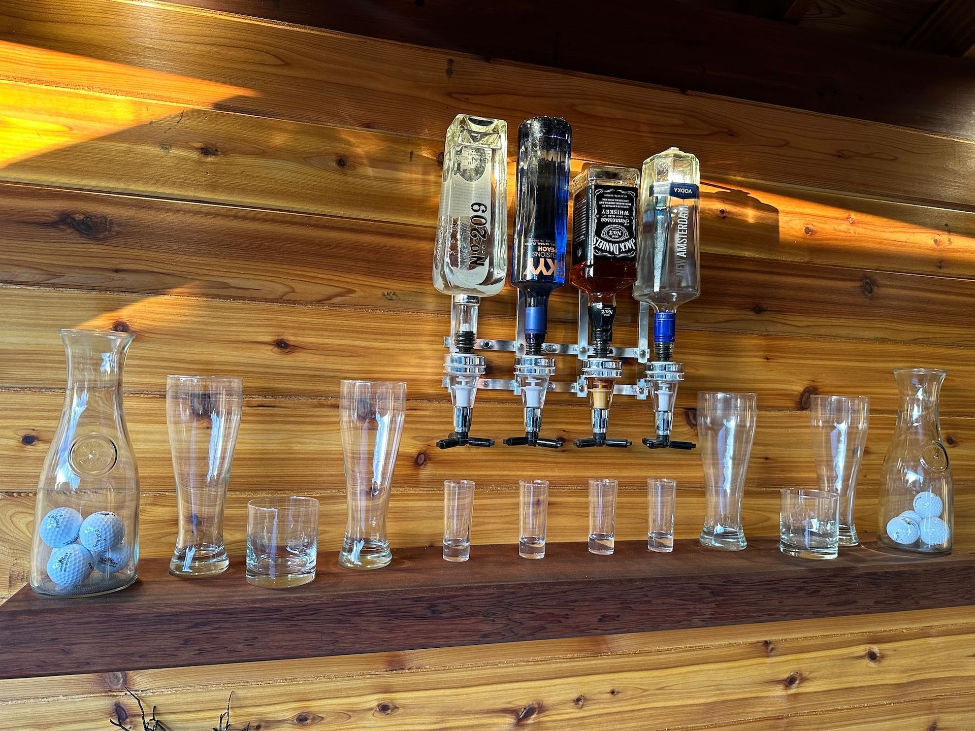A wooden shelf with glasses and bottles on it.