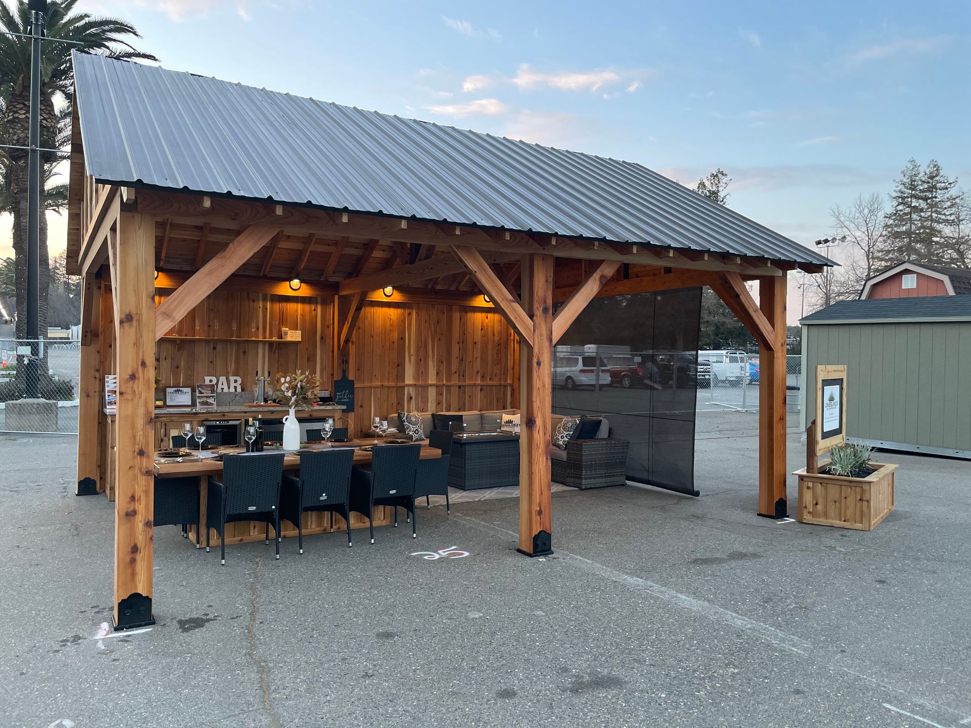 A large wooden structure with a metal roof is sitting in a parking lot.