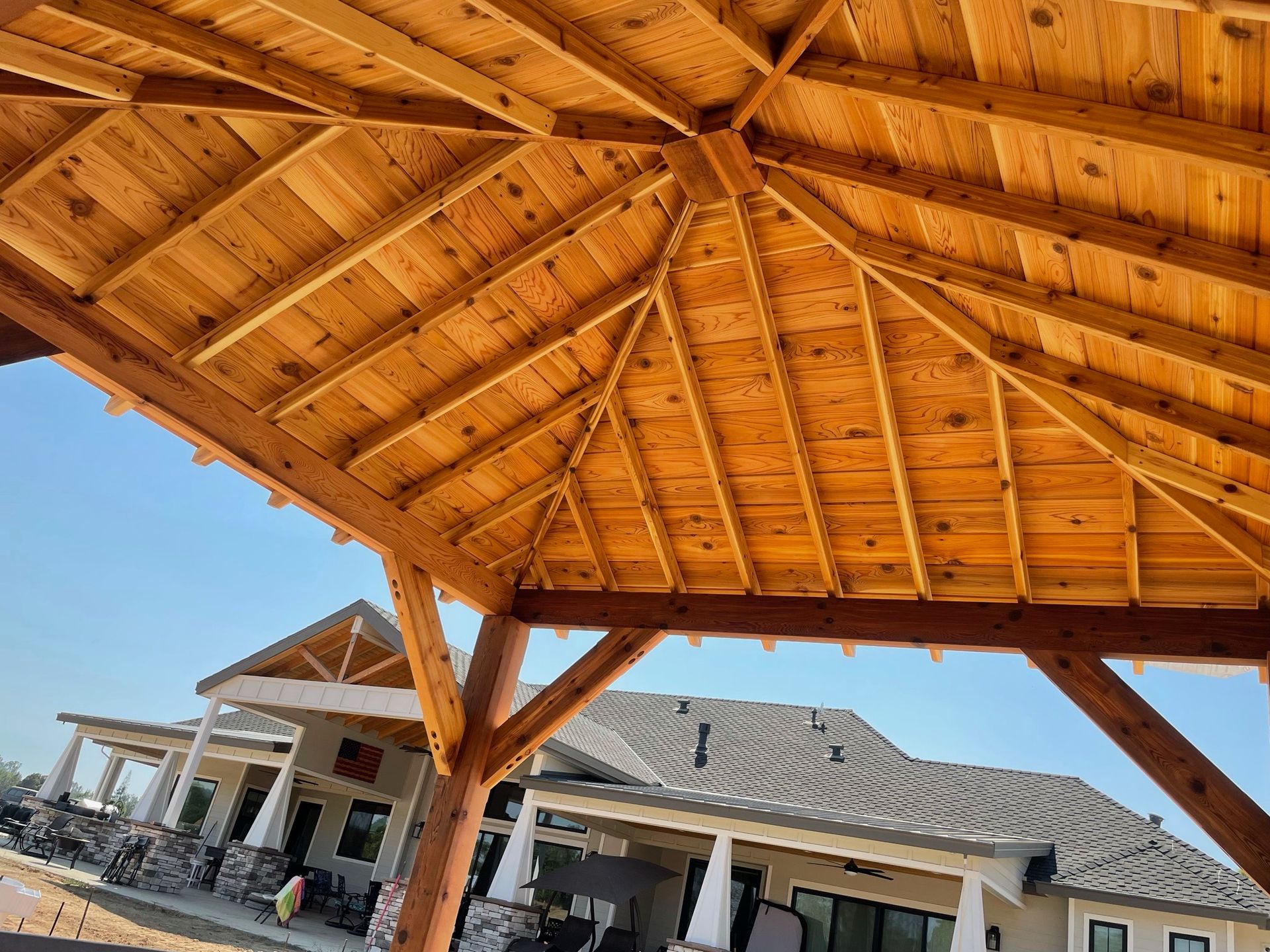 A wooden pavilion with a house in the background.