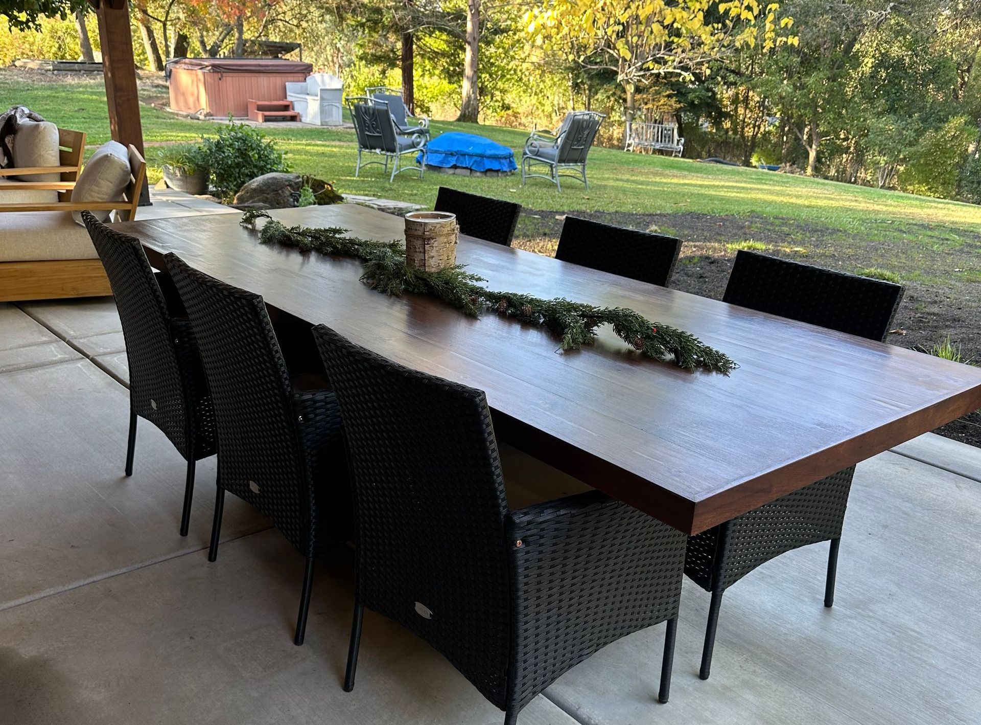 A long wooden table with wicker chairs on a patio