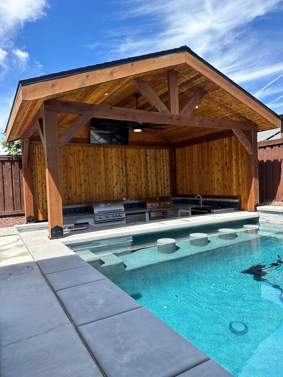 A large swimming pool with a wooden gazebo over it.