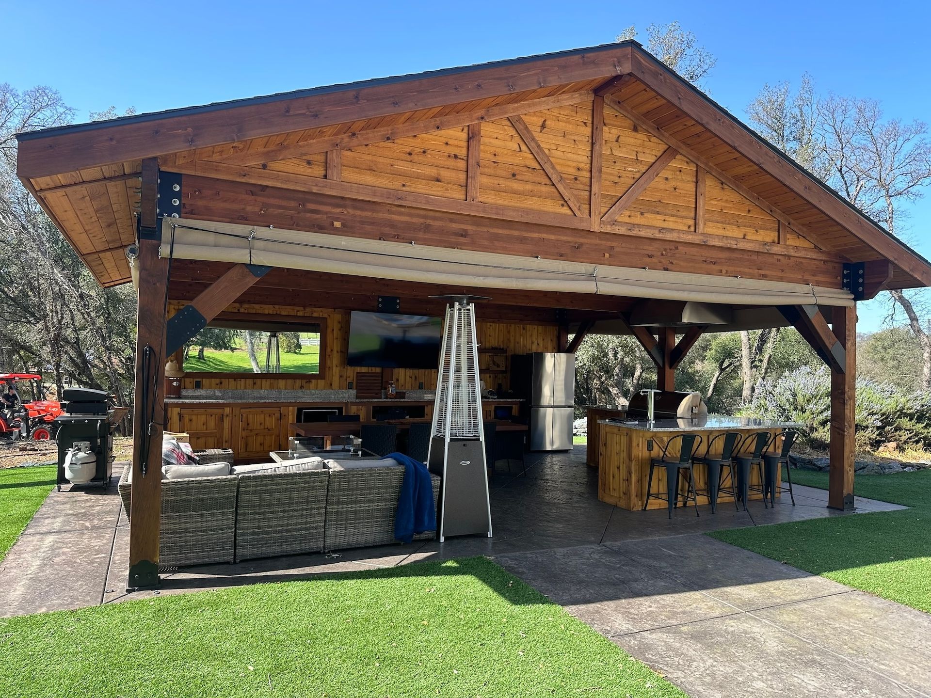 A large wooden pavilion with a kitchen inside of it.