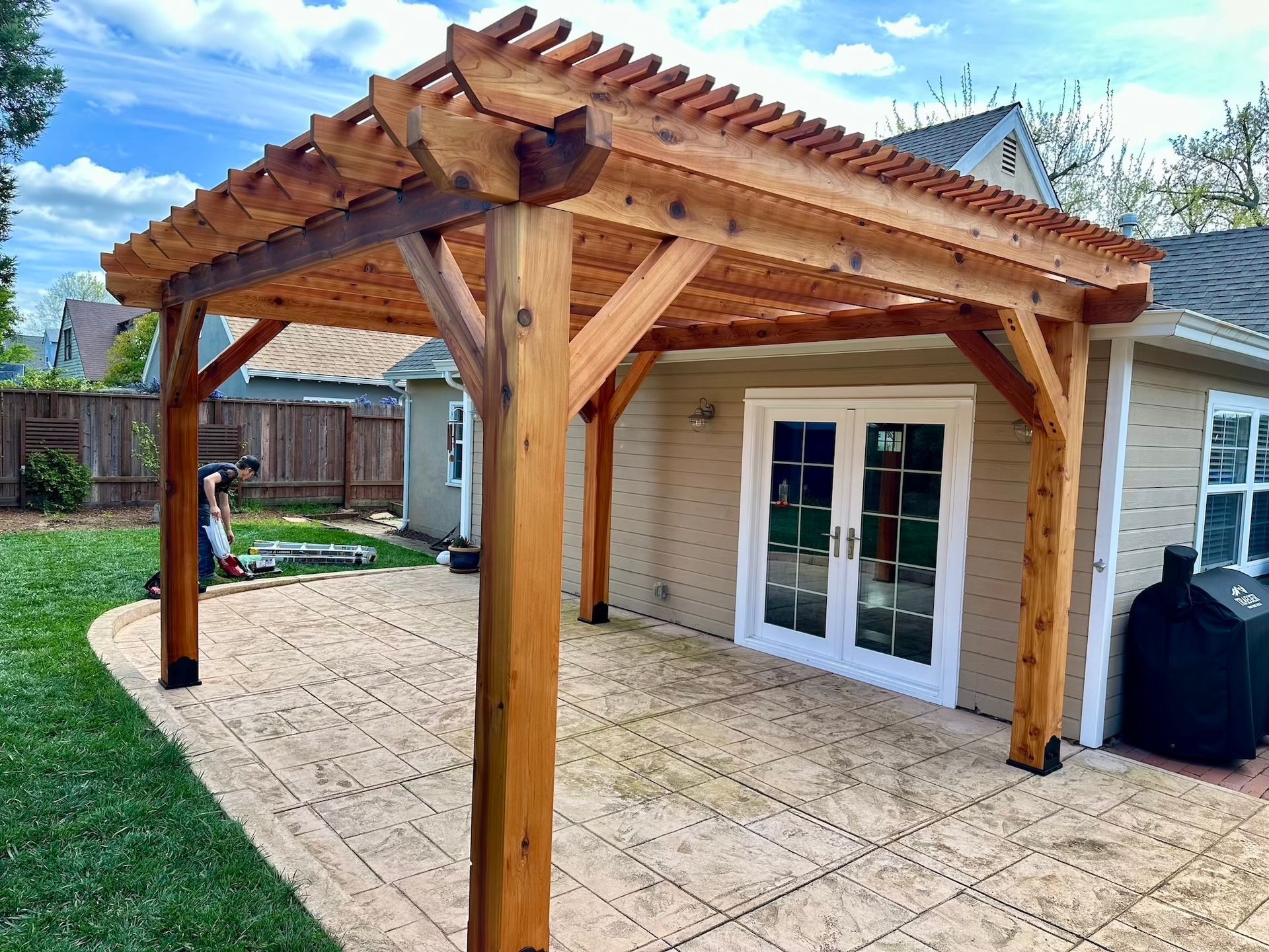 A wooden pergola is sitting in the backyard of a house.