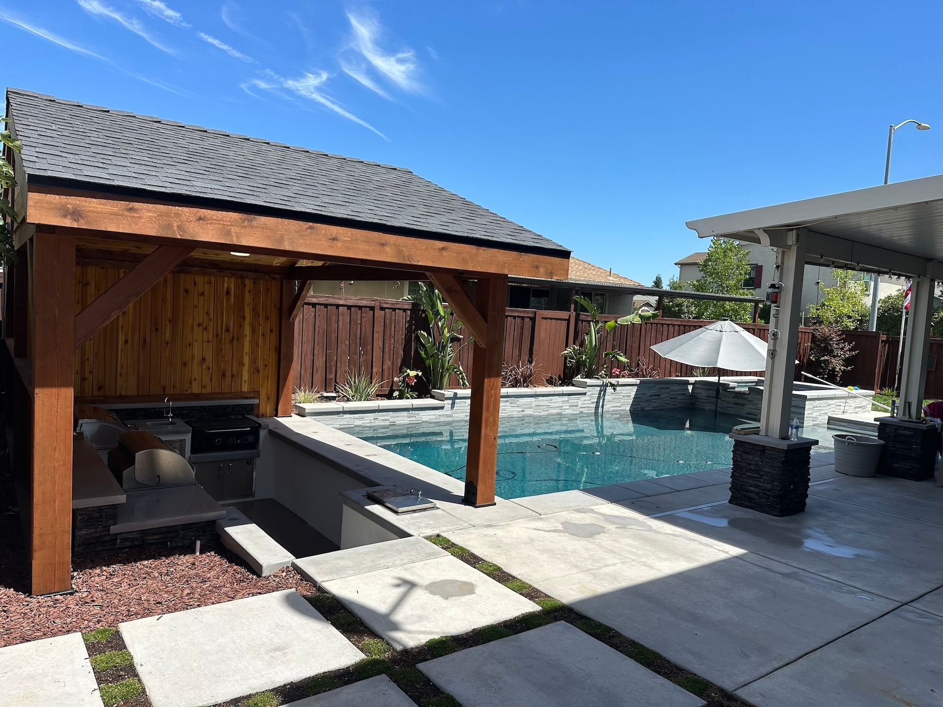 A large swimming pool with a wooden gazebo in the backyard.