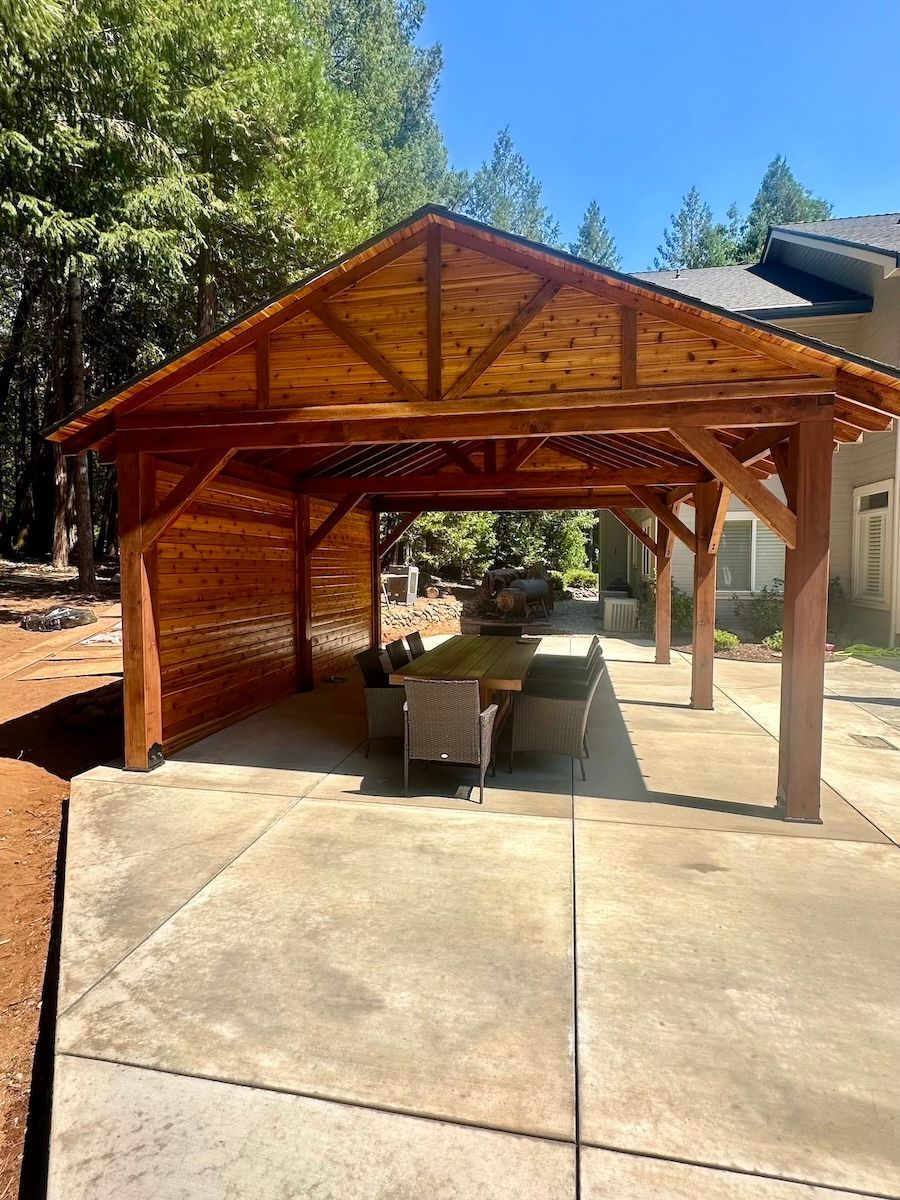 A wooden pavilion with a table and chairs underneath it.