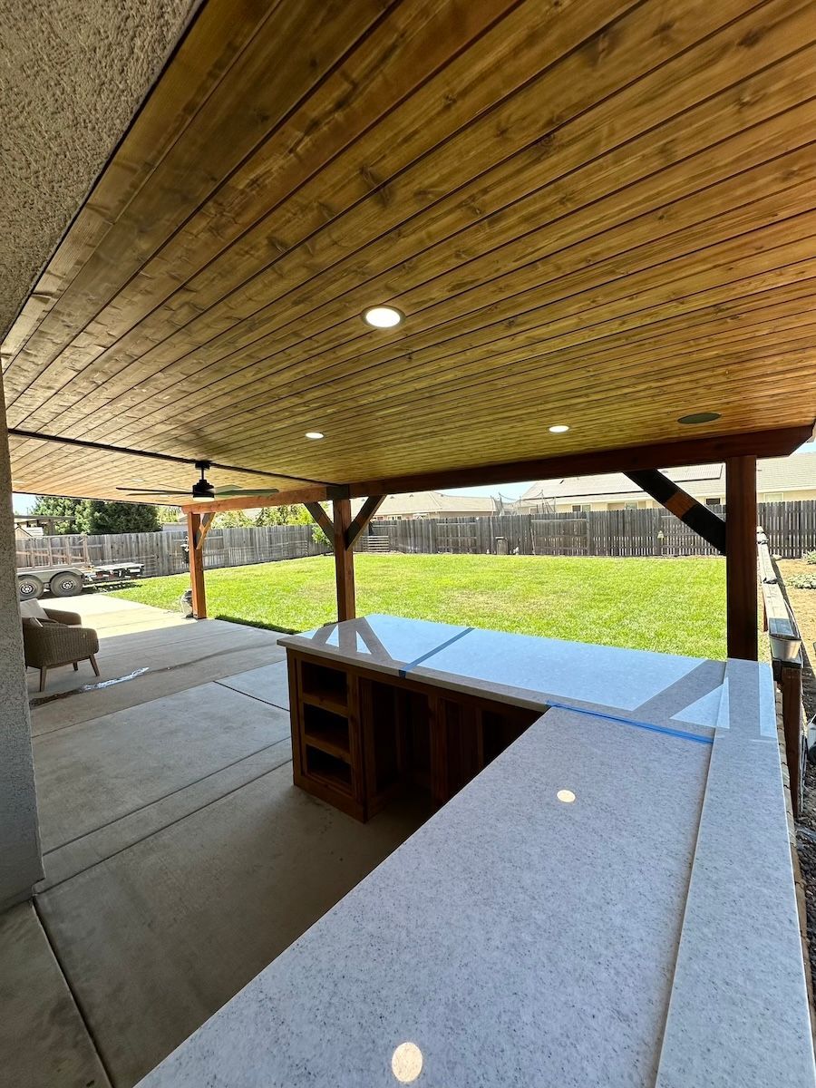 A patio with a wooden ceiling and a large counter top.