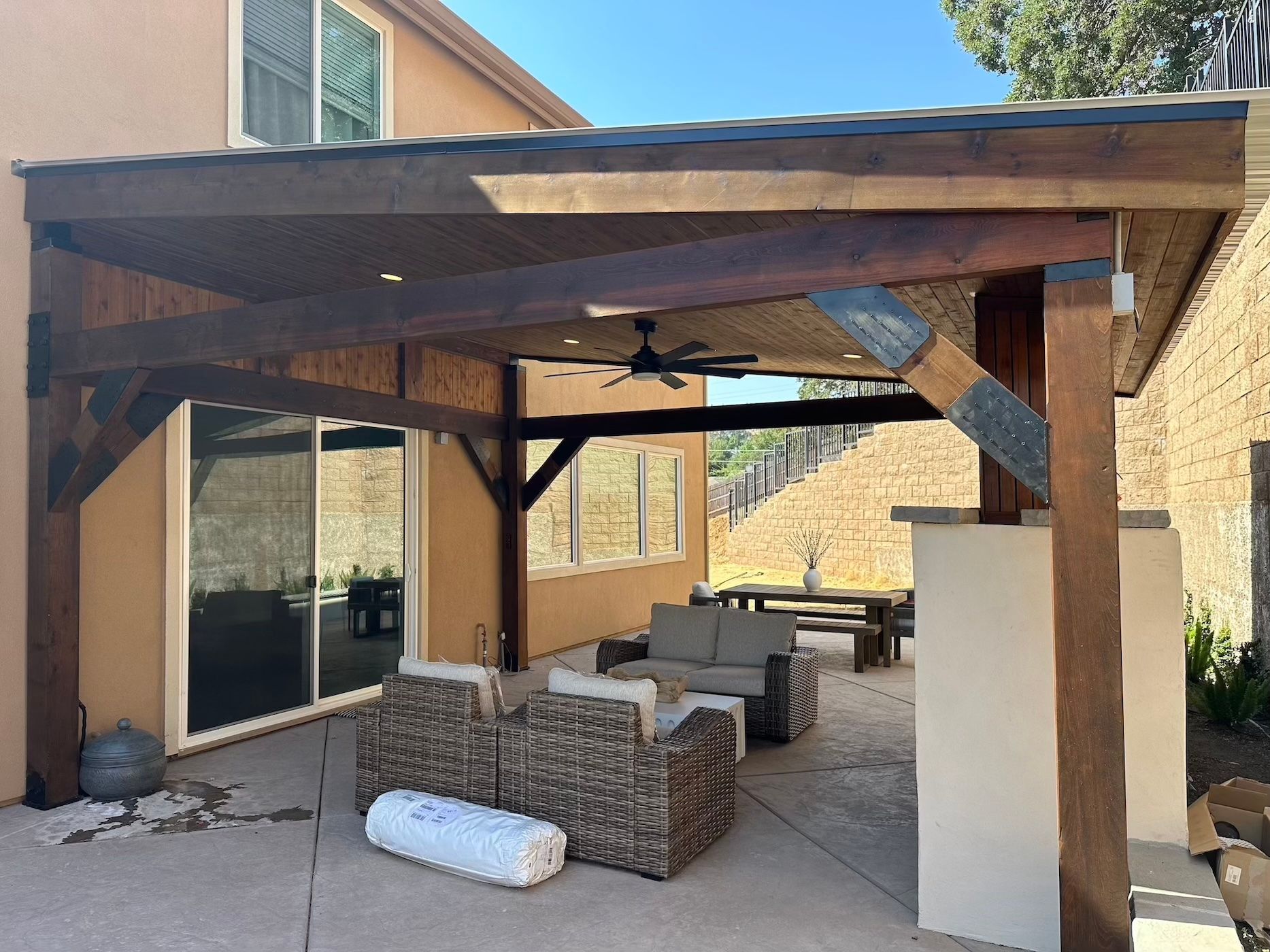 A patio with wicker furniture under a wooden pergola.