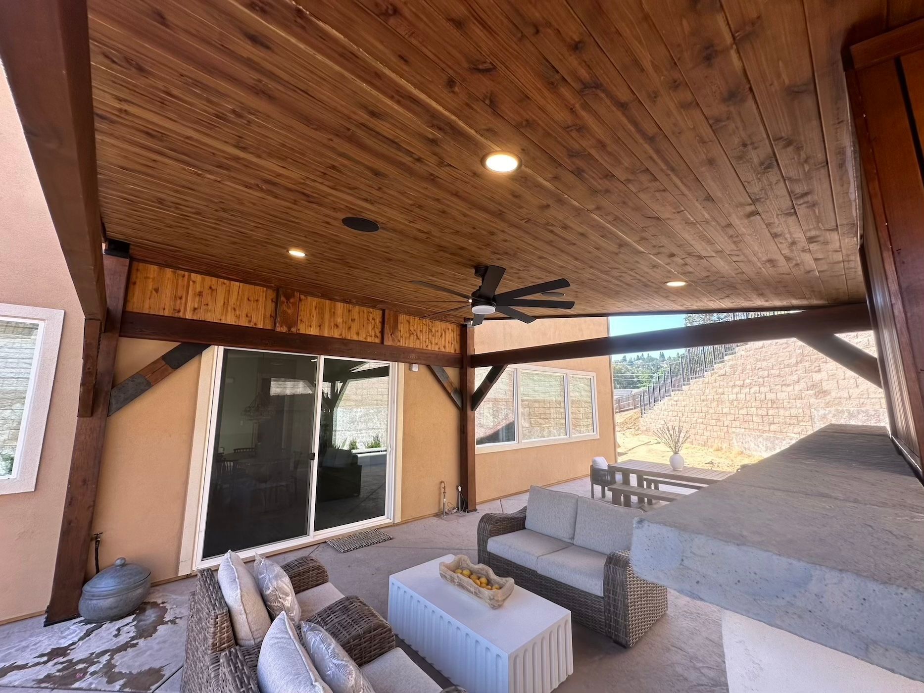 A patio with a couch , table , and ceiling fan.