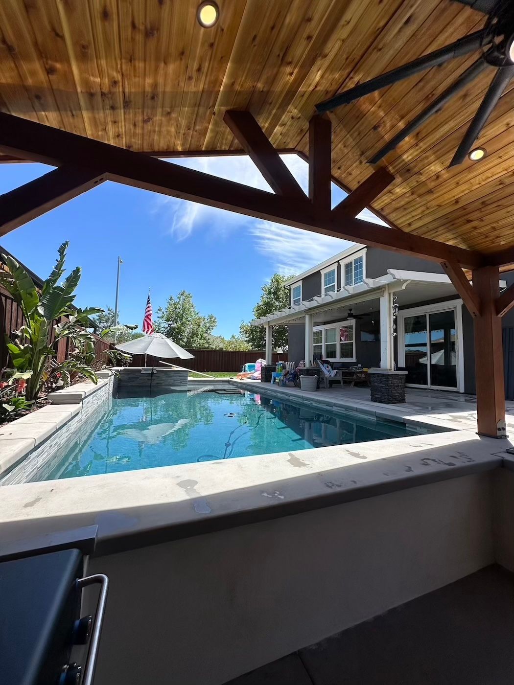 There is a large swimming pool in the backyard of a house.