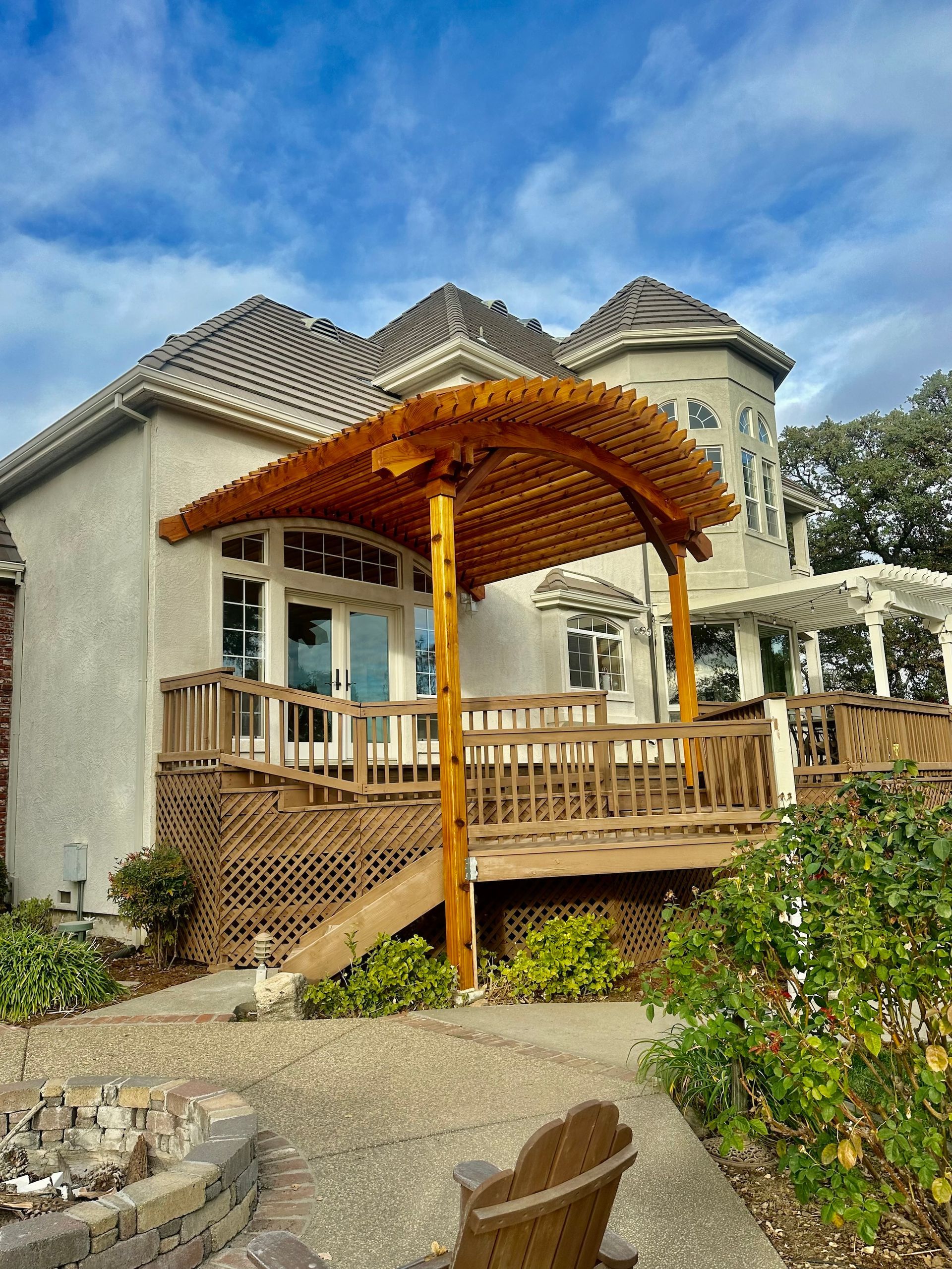 a large white house with a wooden pergola over the deck .