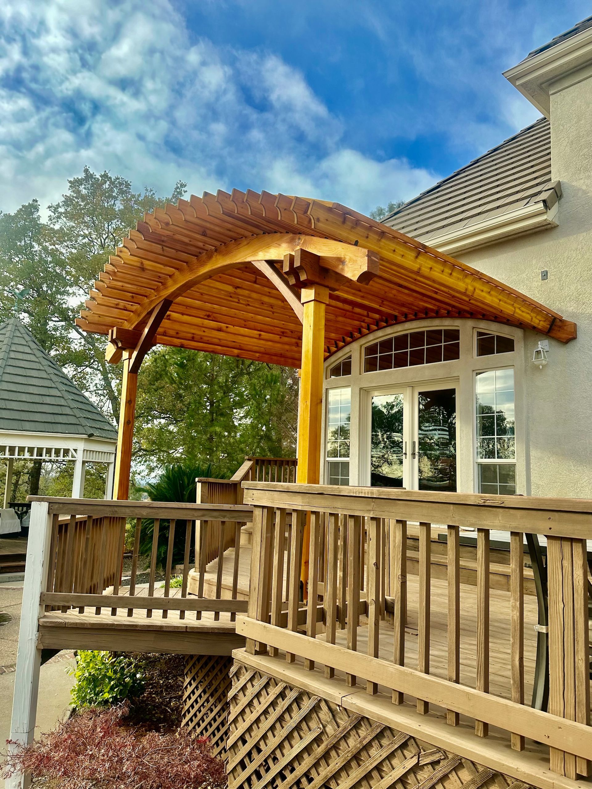 a wooden gazebo is sitting on top of a wooden deck next to a house .