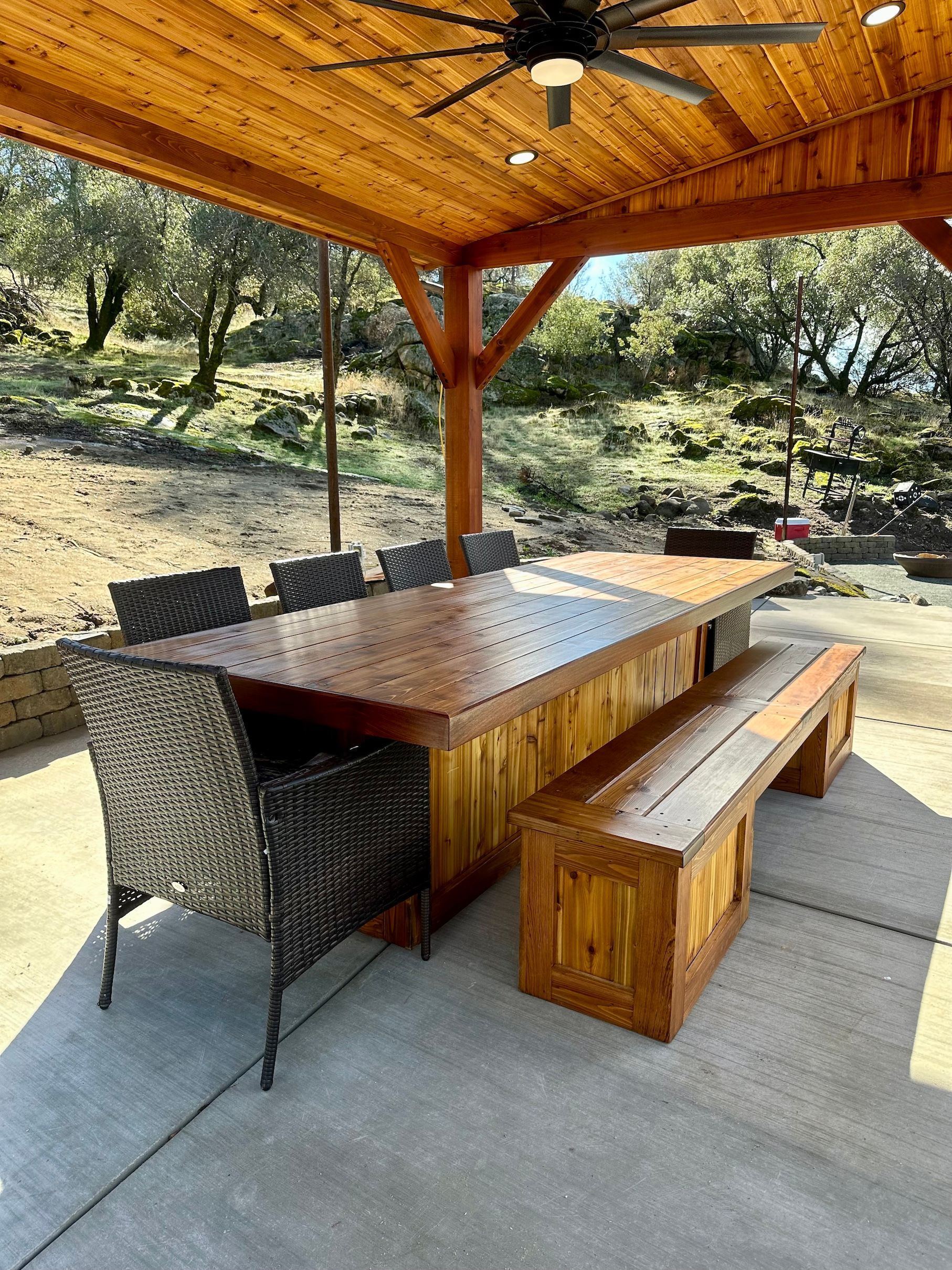 a wooden table with chairs and a bench under a ceiling fan .