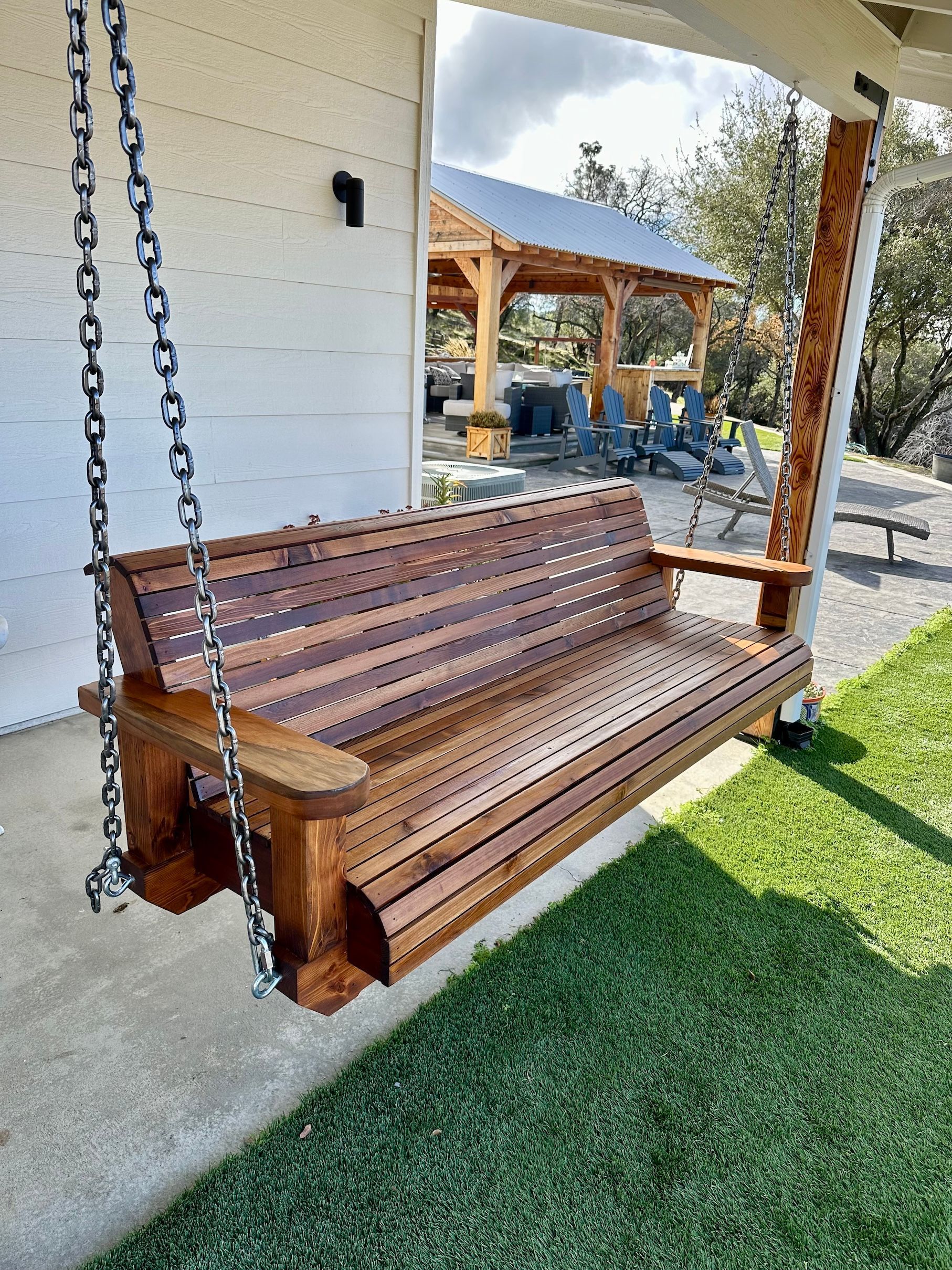 a wooden porch swing is hanging from chains on a porch .