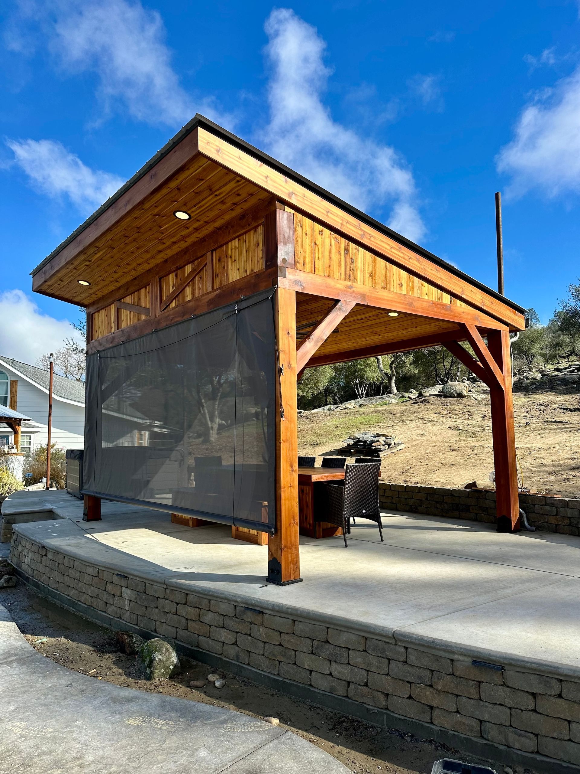 a wooden gazebo with a table and chairs underneath it .