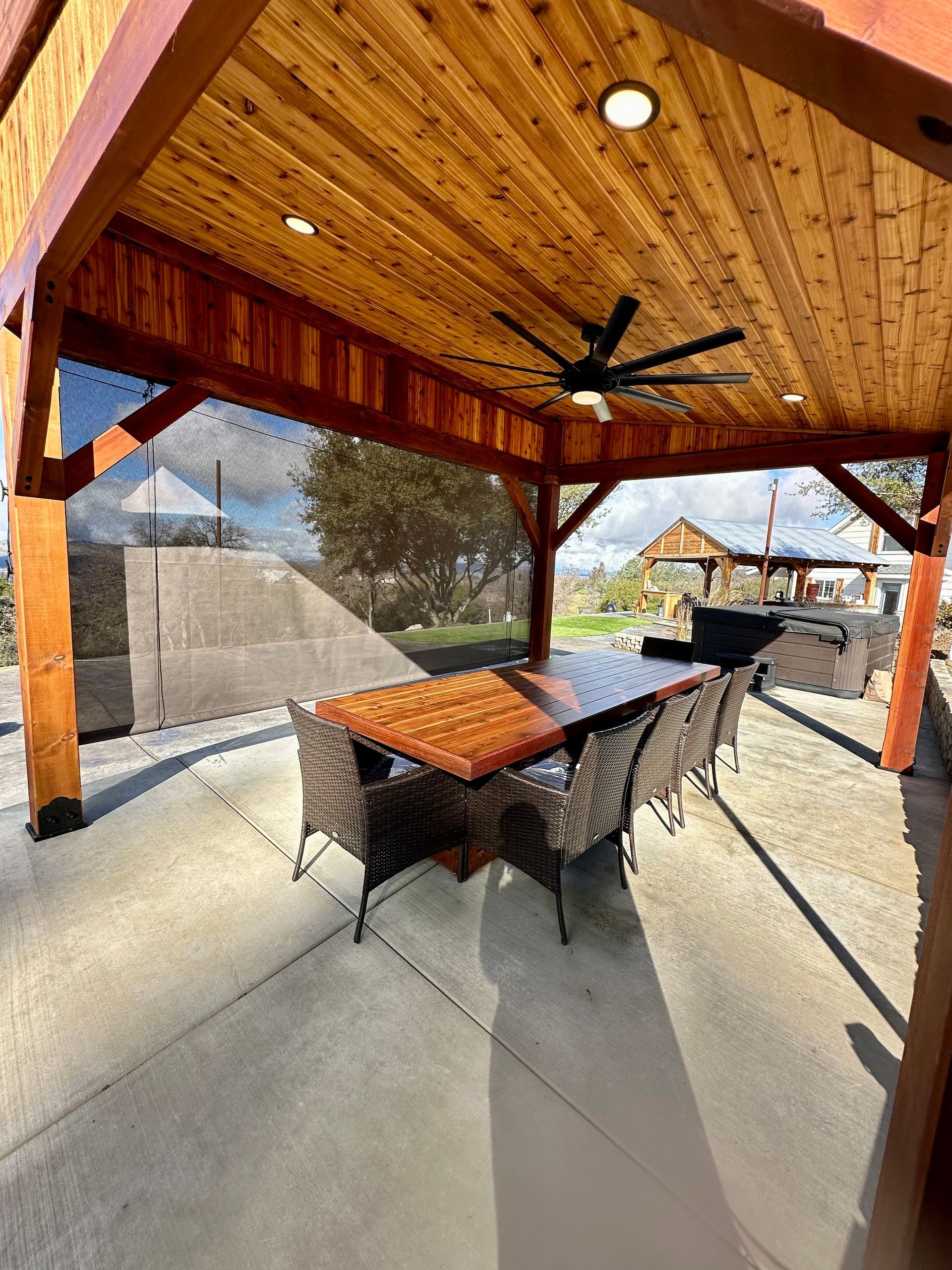 a wooden gazebo with a table and chairs underneath it .
