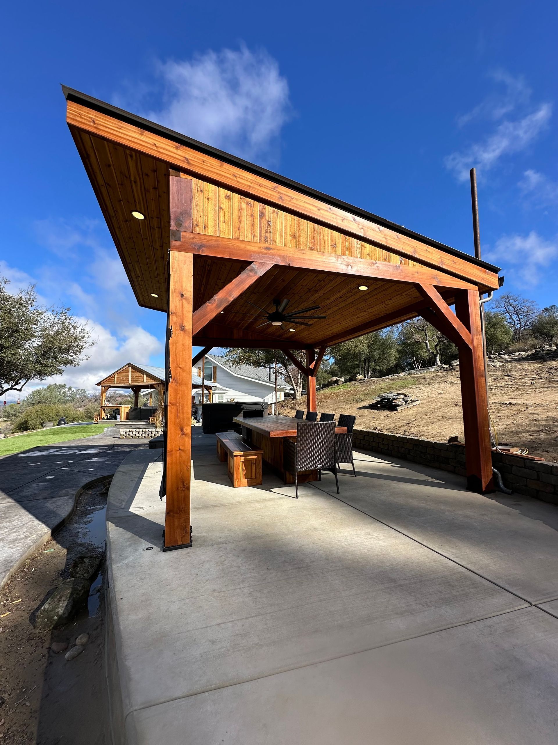 a wooden pavilion with a table and chairs underneath it .