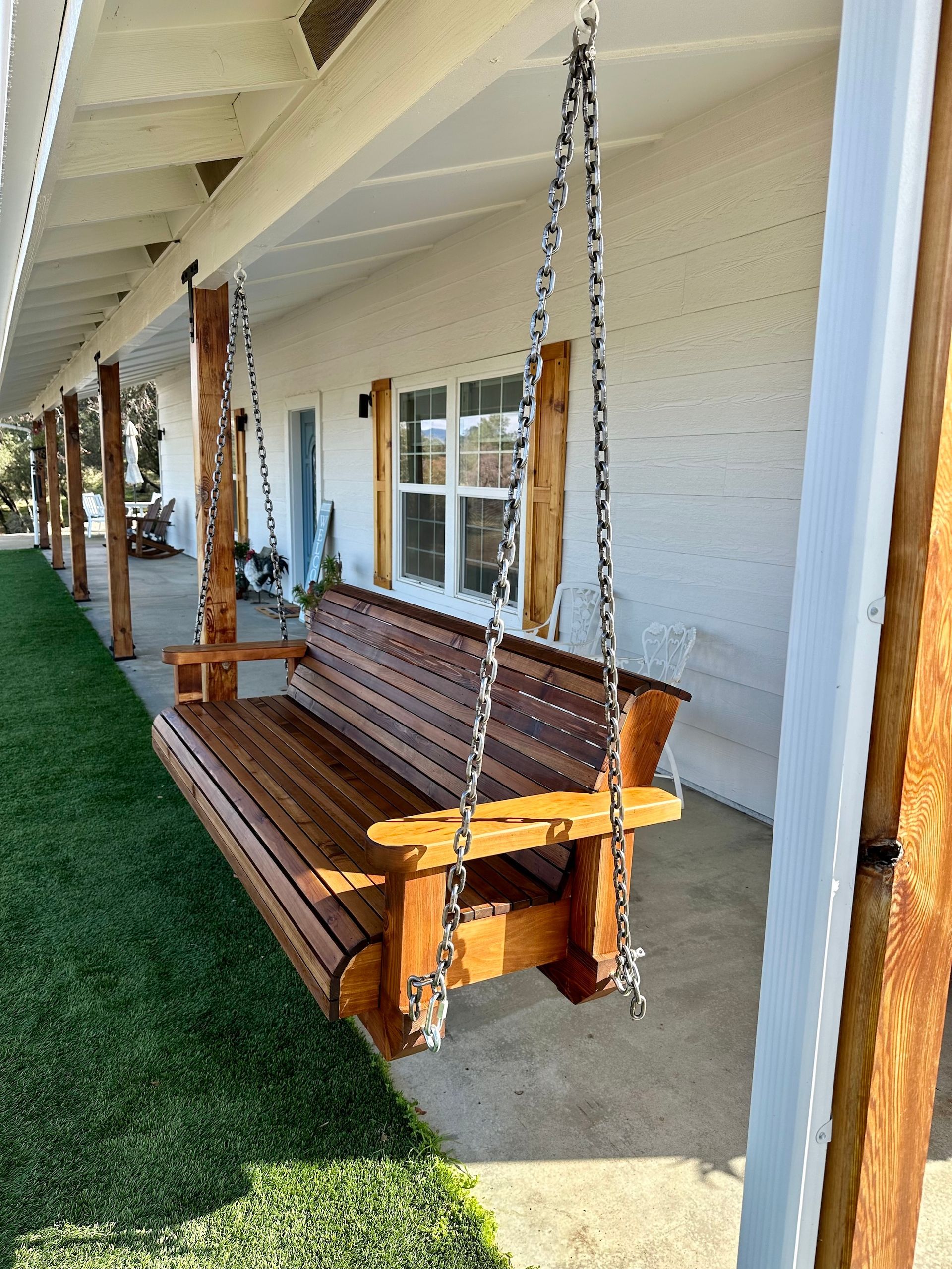 a wooden porch swing is hanging from a white building .