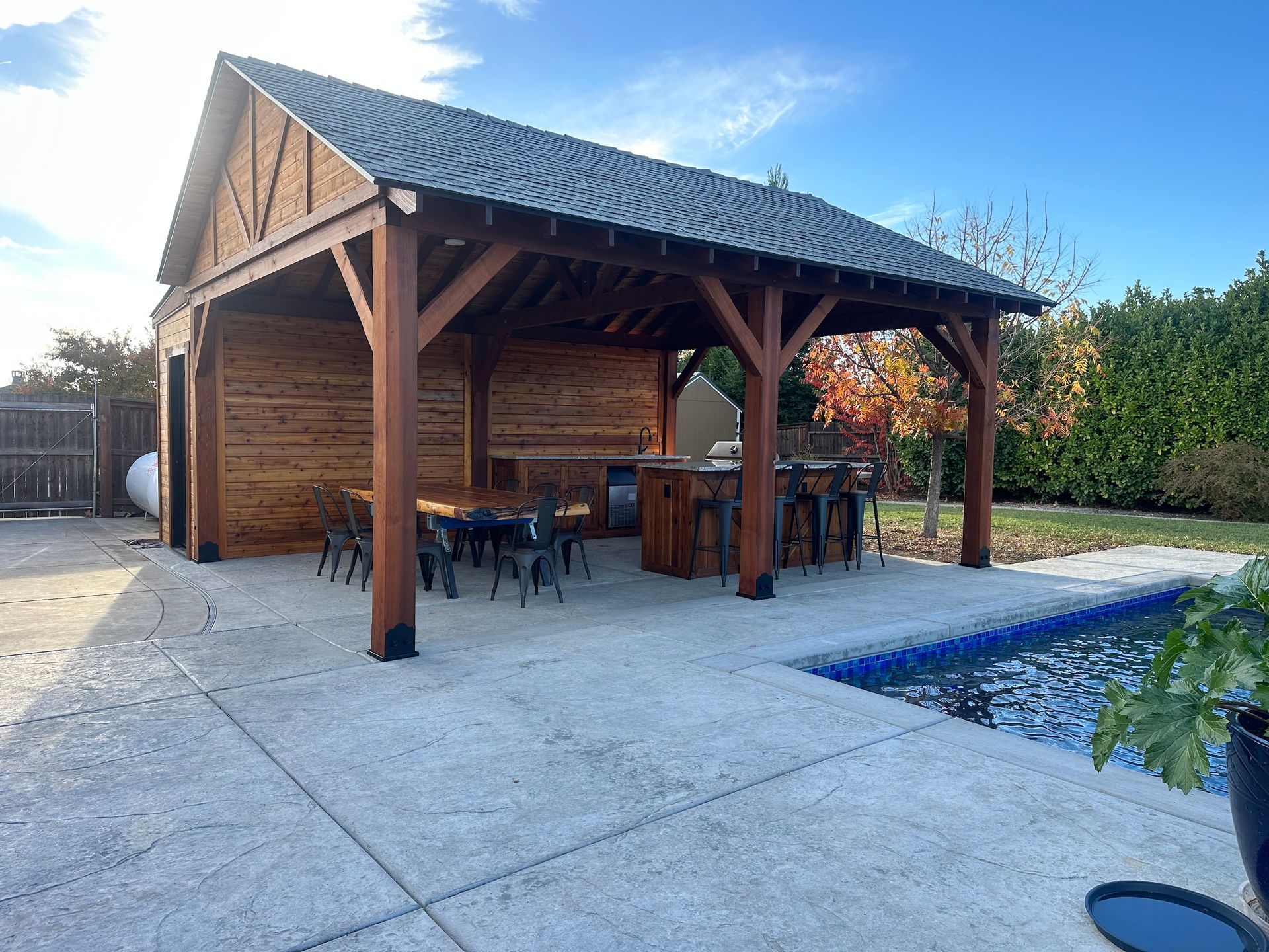 a wooden pavilion with a table and chairs next to a pool .