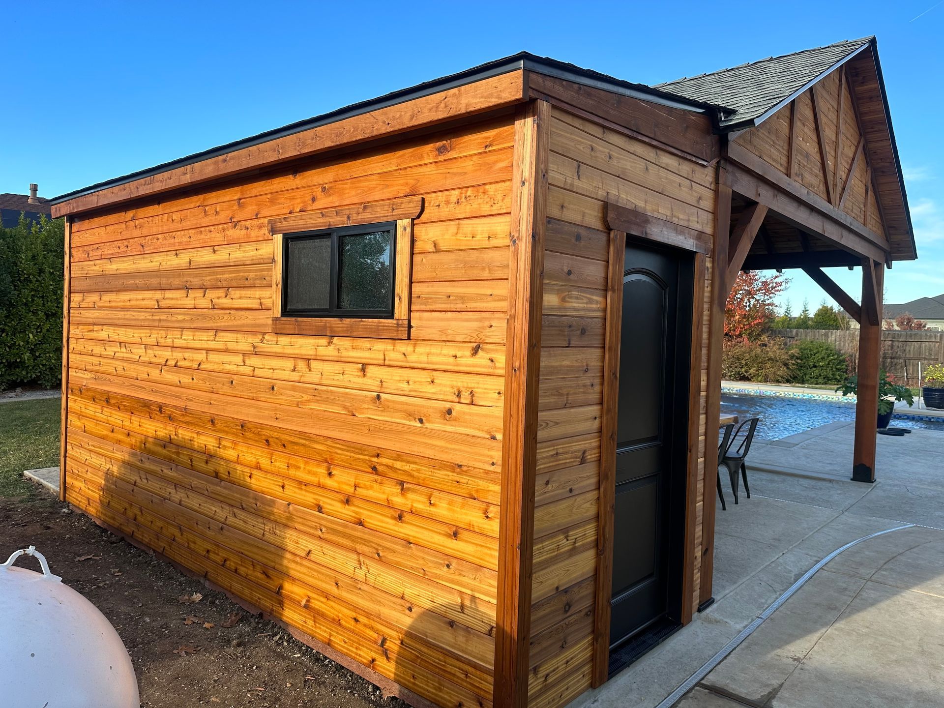 a wooden shed is sitting next to a swimming pool .