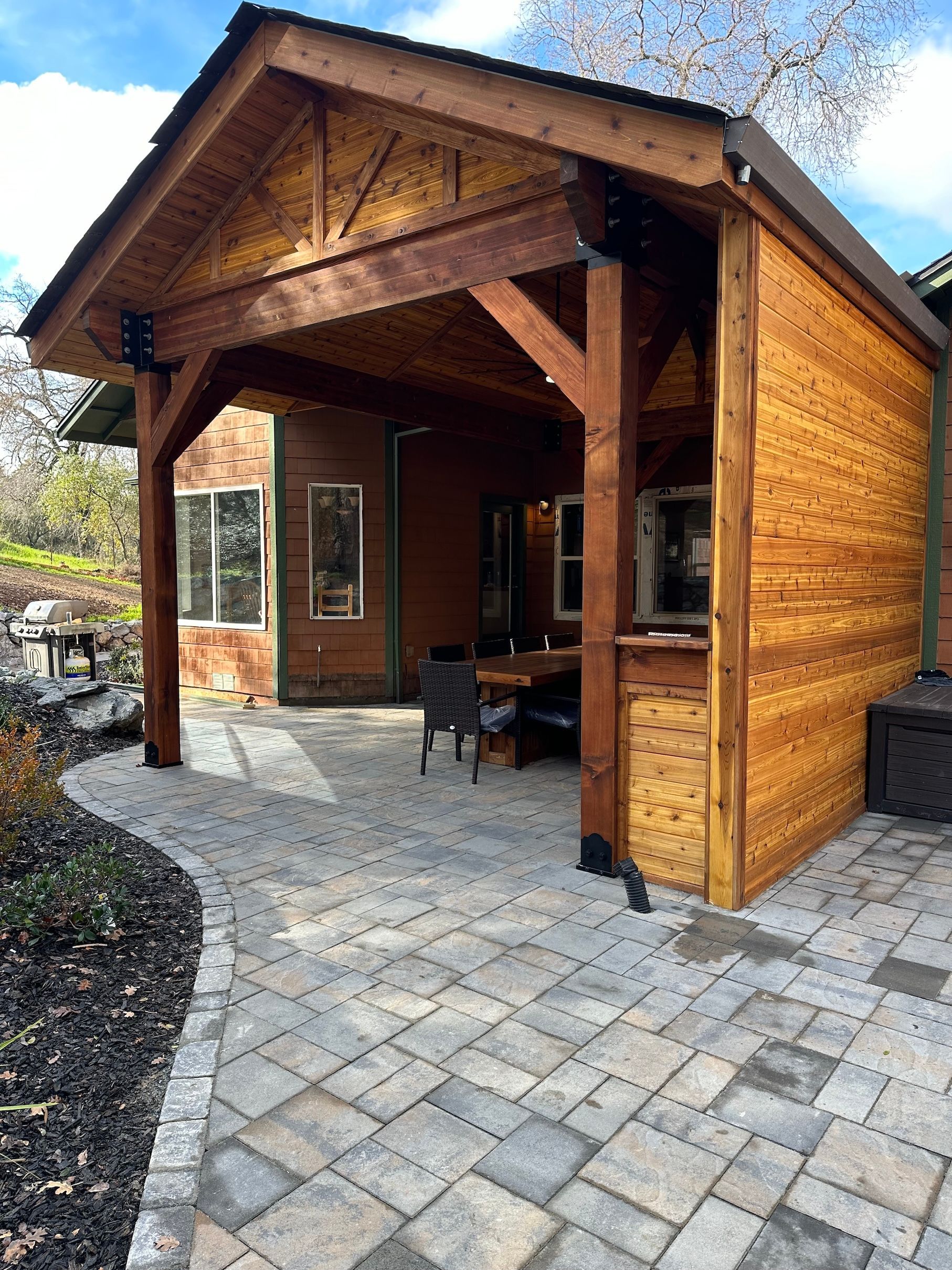 a wooden pavilion with a brick patio in front of a house .