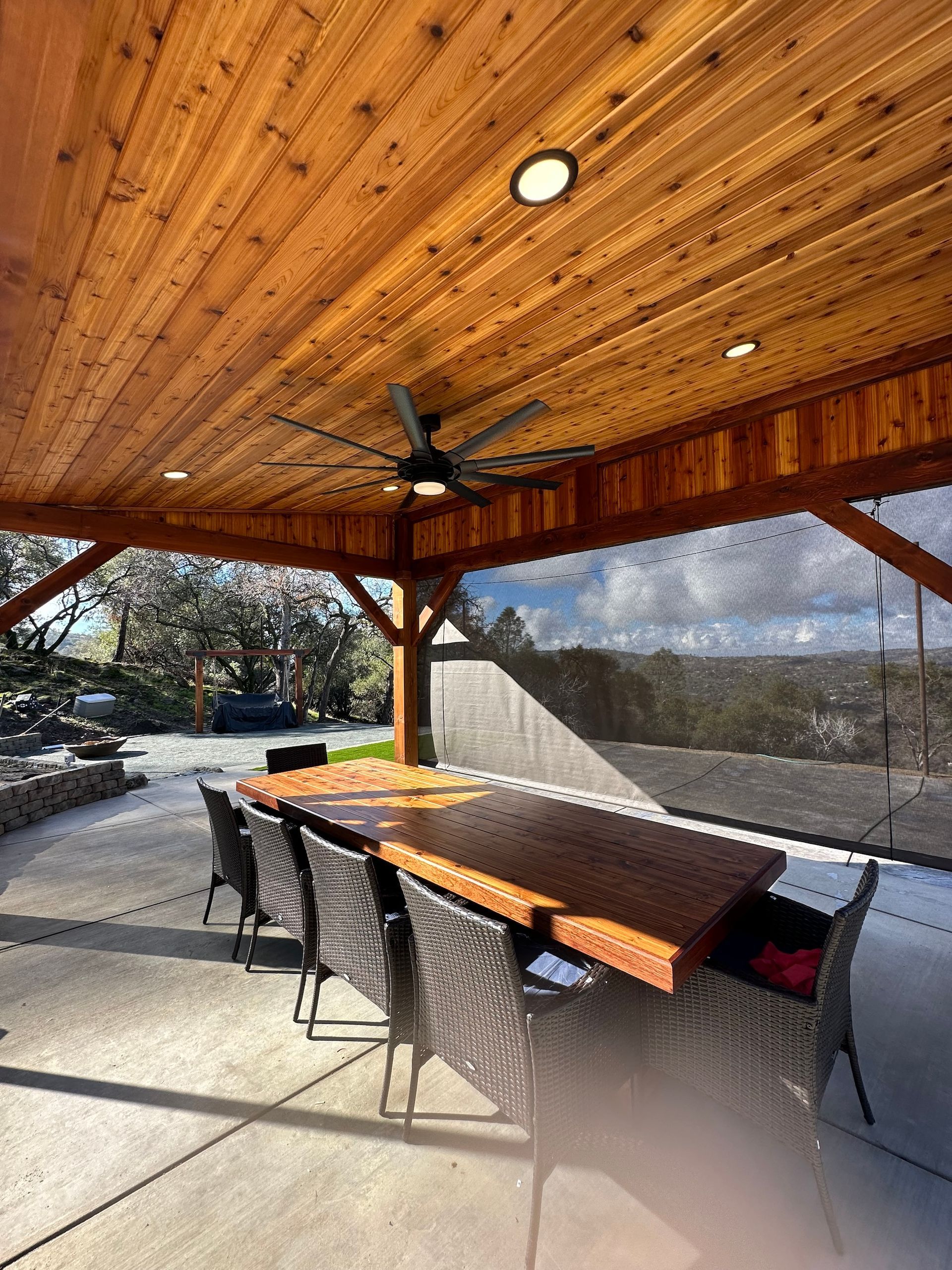 a wooden table and chairs under a wooden ceiling with a ceiling fan .