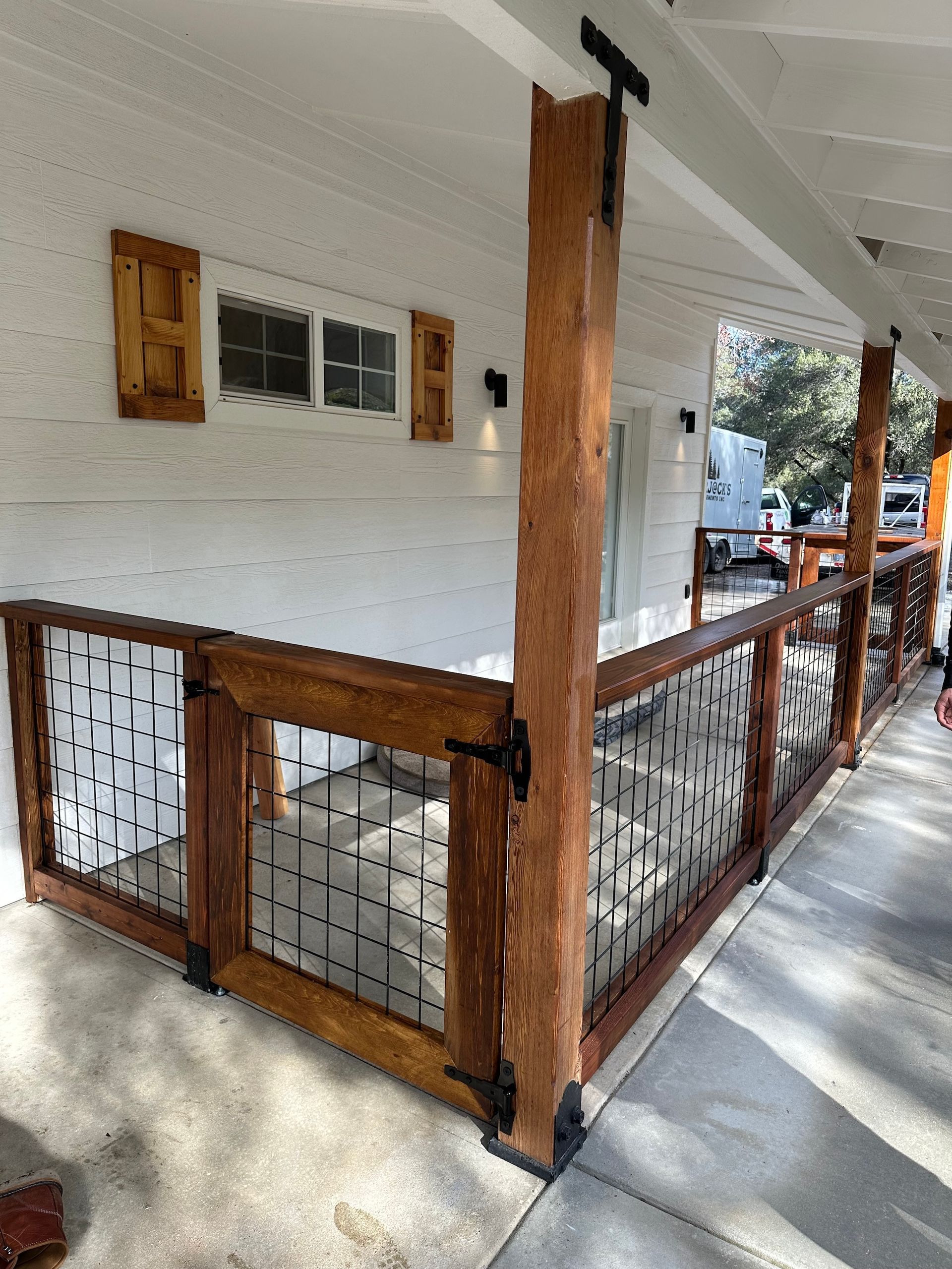 a porch with a wooden railing and a metal fence