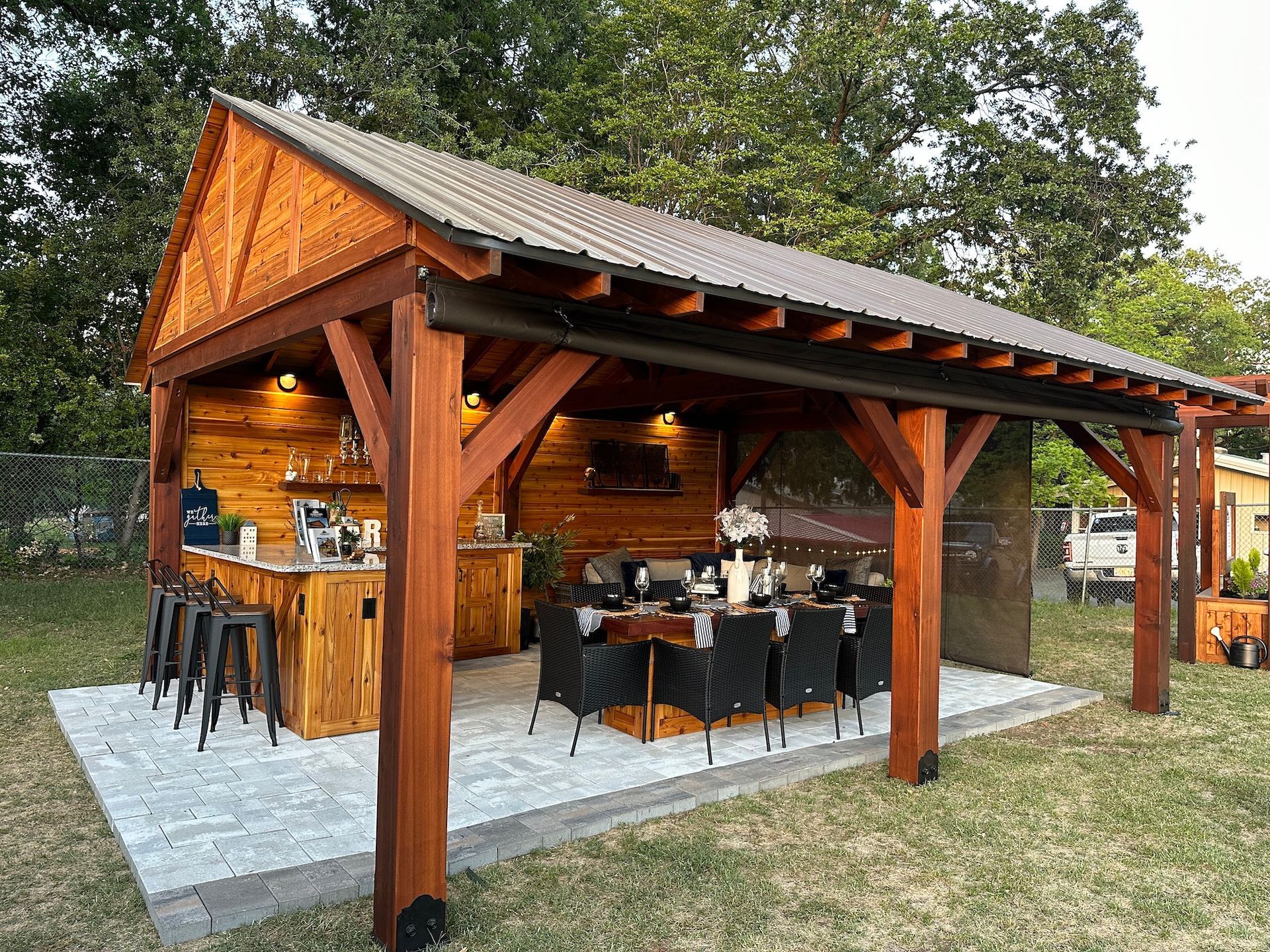 A large wooden pavilion with a table and chairs underneath it.