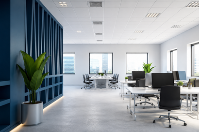 Modern open office with desks, chairs, computers, and large blue divider with potted plants
