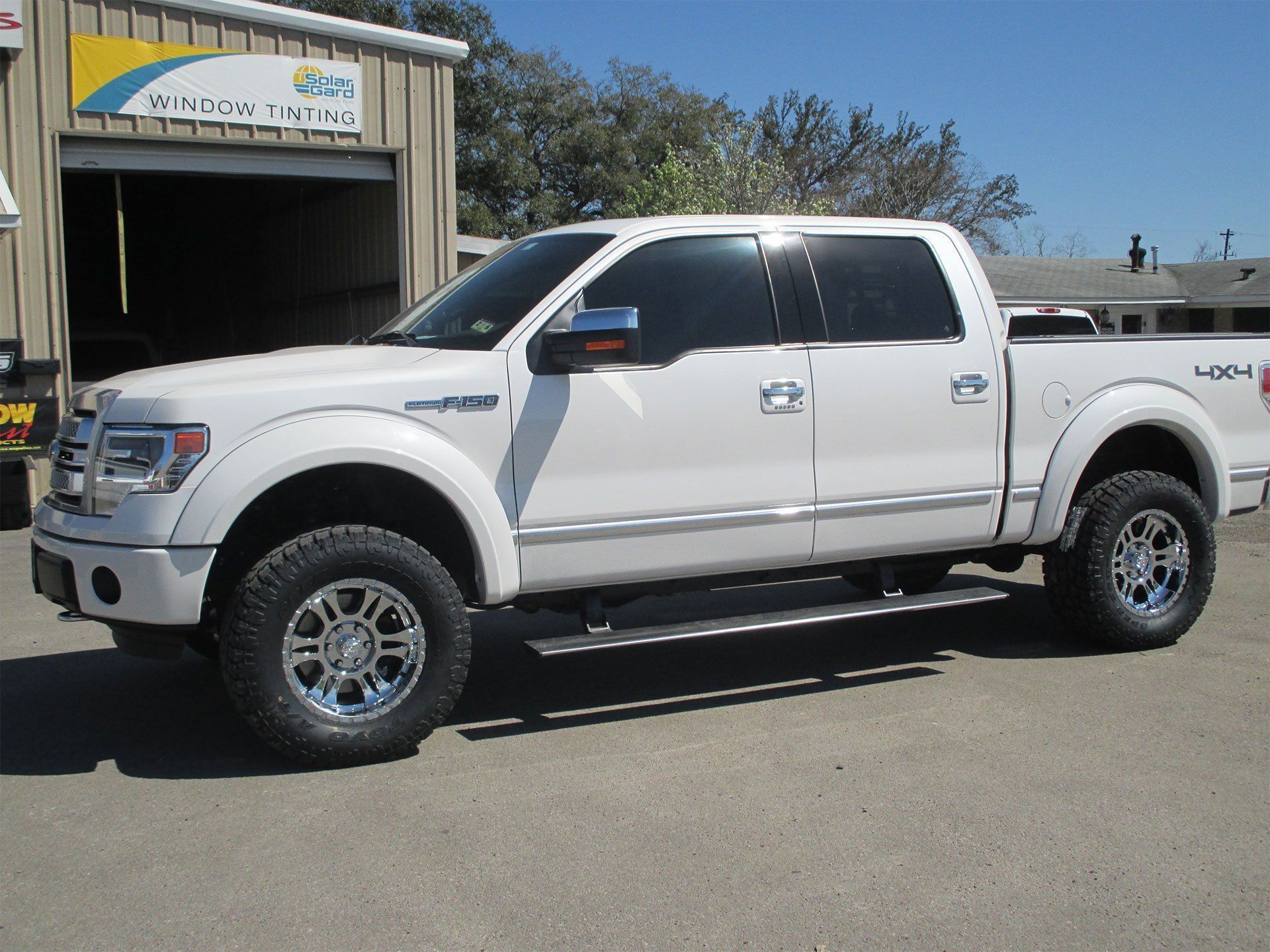 A white pickup truck is parked in front of a garage