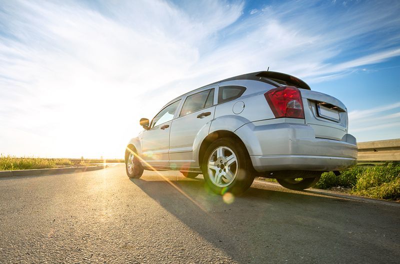 A white car is parked on the side of a road.