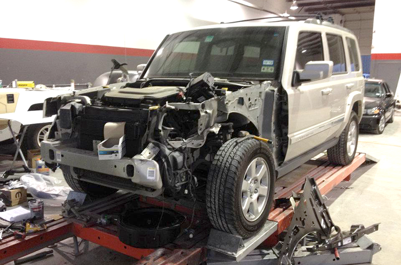 A jeep is being repaired in a garage with the hood off