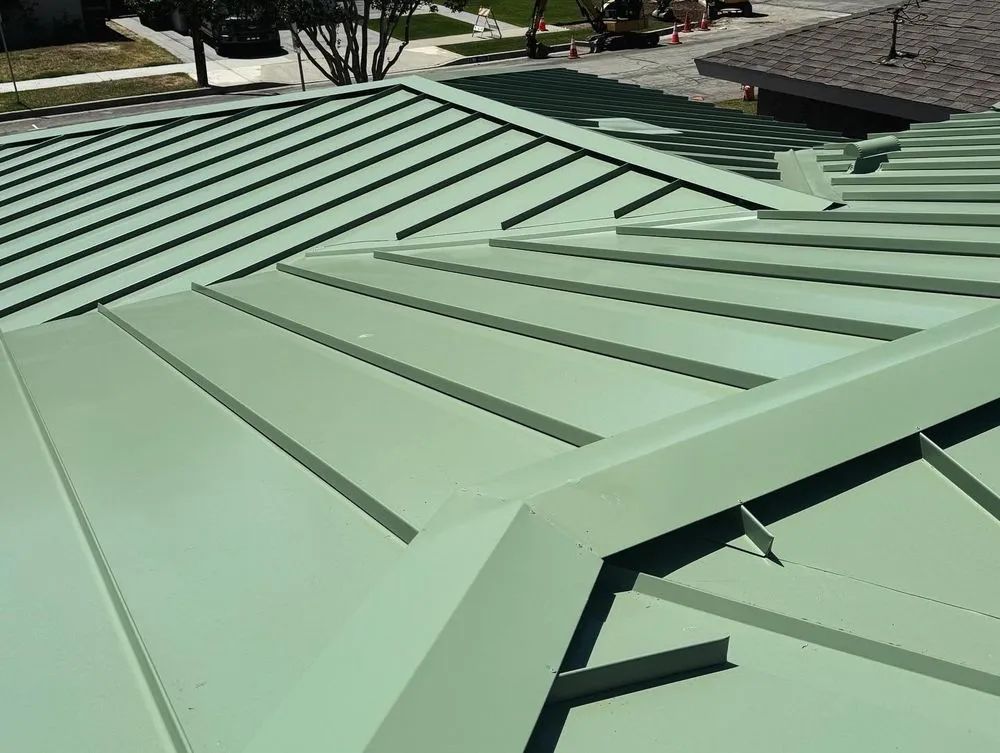 Green metal roof with standing seams and skylights on a building