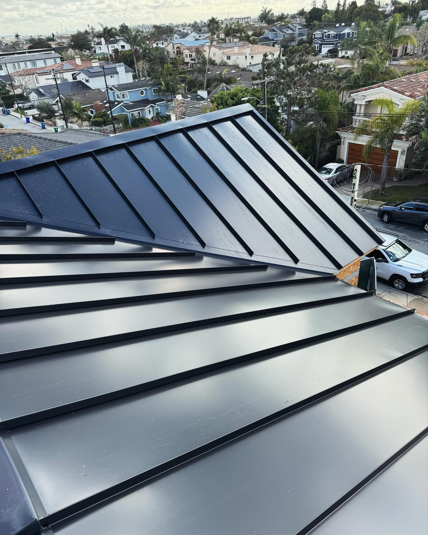 A close up of a black metal roof with a city in the background.
