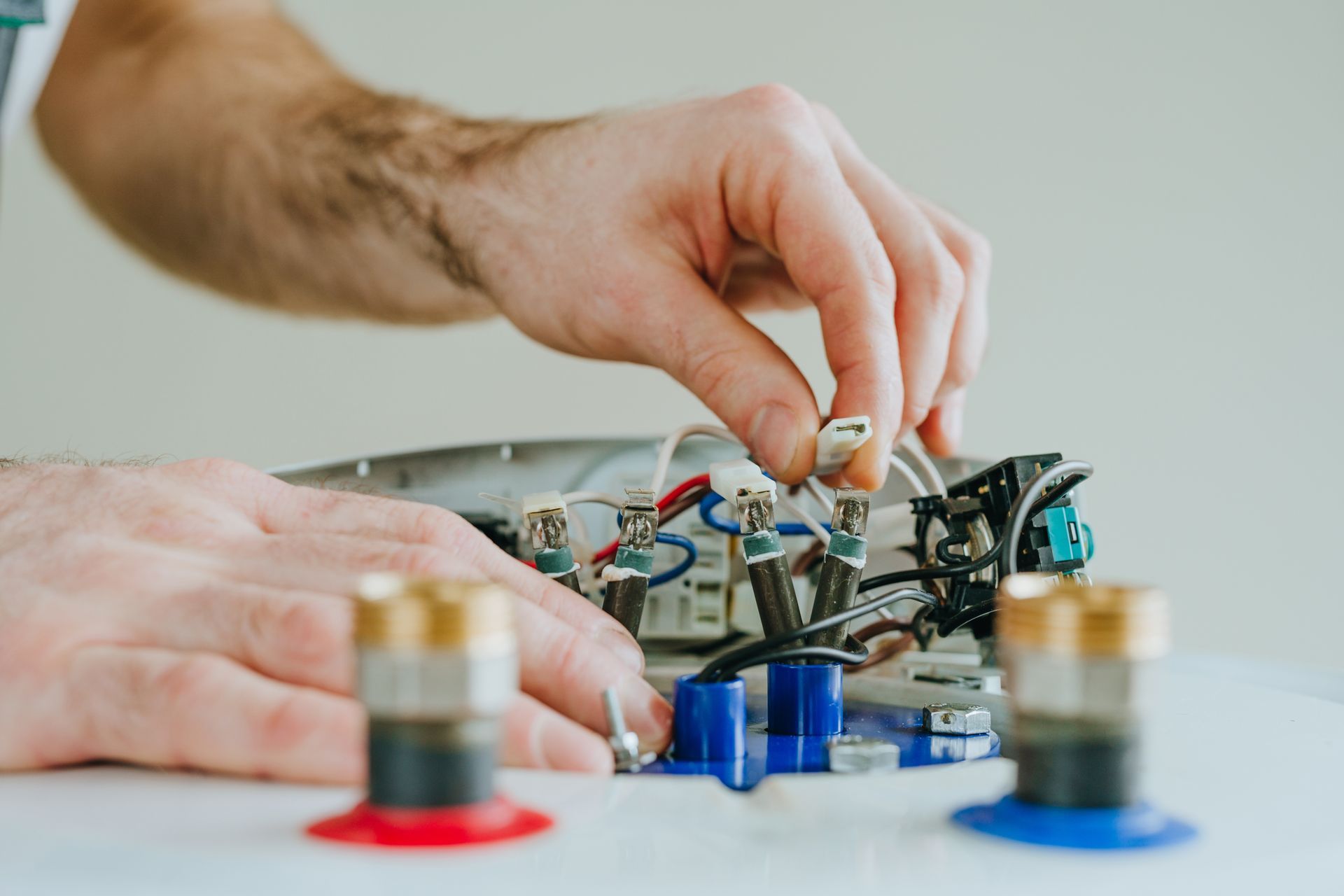 Hands assembling a small electronic circuit with red and blue components on a table