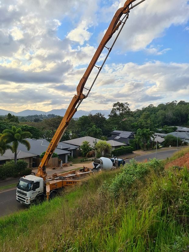 A Concrete Pump Truck Is Sitting On Top Of A Grassy Hill — B & C Donnachie Concrete Contractors in Atherton, QLD