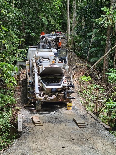 A Concrete Pump Is Sitting On The Side Of A Road In The Woods — B & C Donnachie Concrete Contractors in Kuranda, QLD