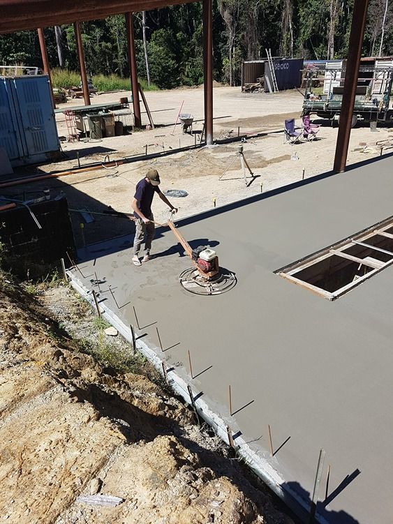 A Man Is Spreading Concrete On A Construction Site — B & C Donnachie Concrete Contractors in Kuranda, QLD