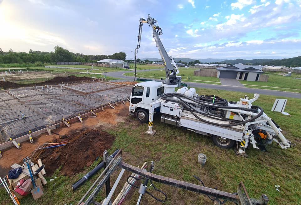 A Concrete Pump Truck Is Pumping Concrete On A Construction Site — B & C Donnachie Concrete Contractors in Smithfield, QLD