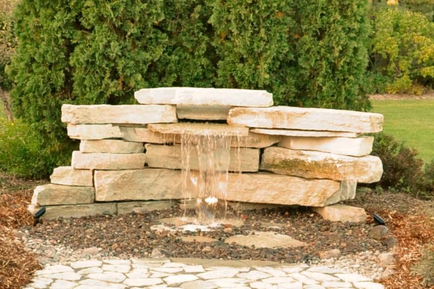 A Waterfall Made Of Rocks In A Garden With Trees In The Background — Menasha, WI — Artscapes COC