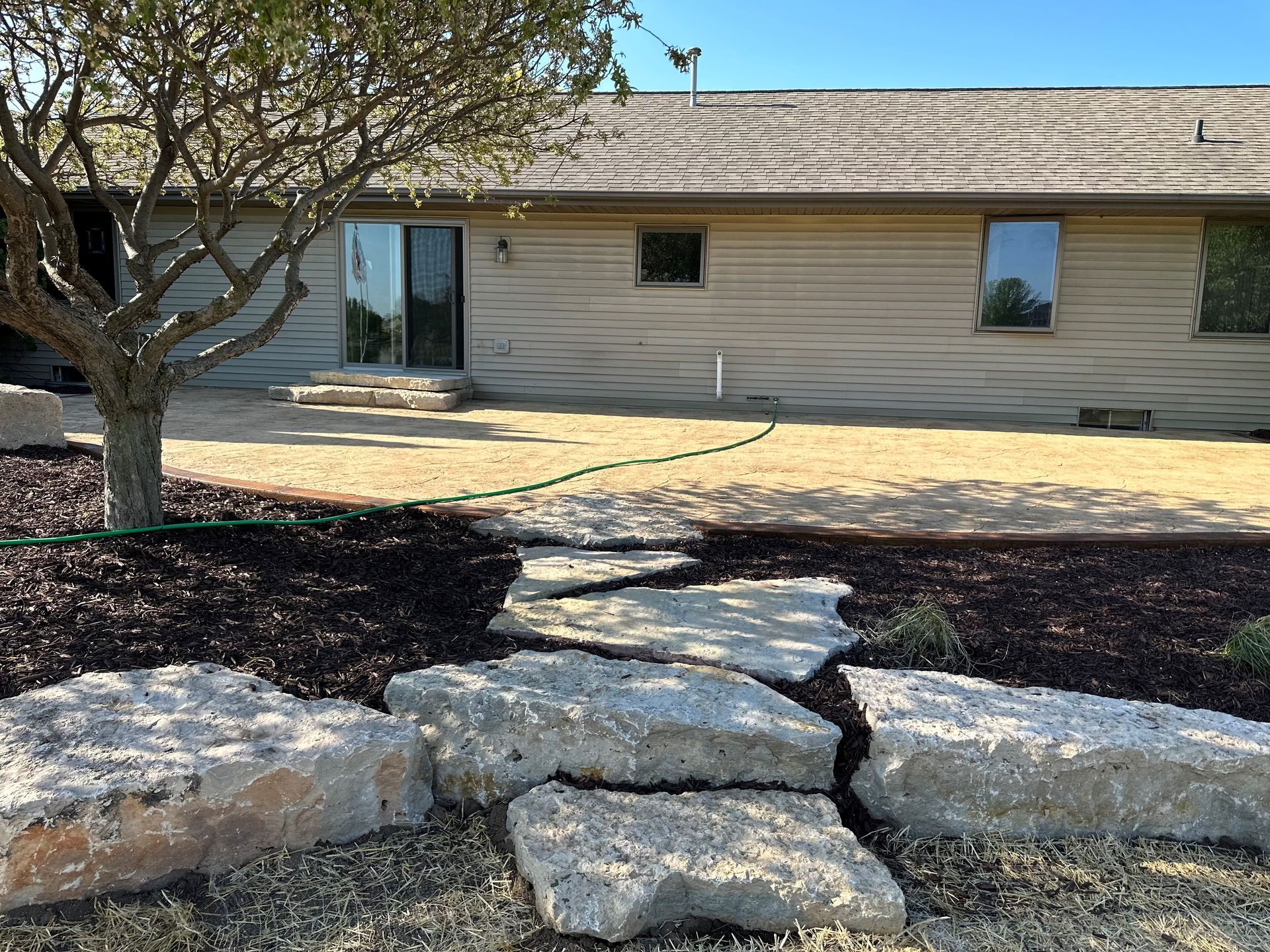 Natural flagstone walkway with limestone stepping stones leading to a beige siding home