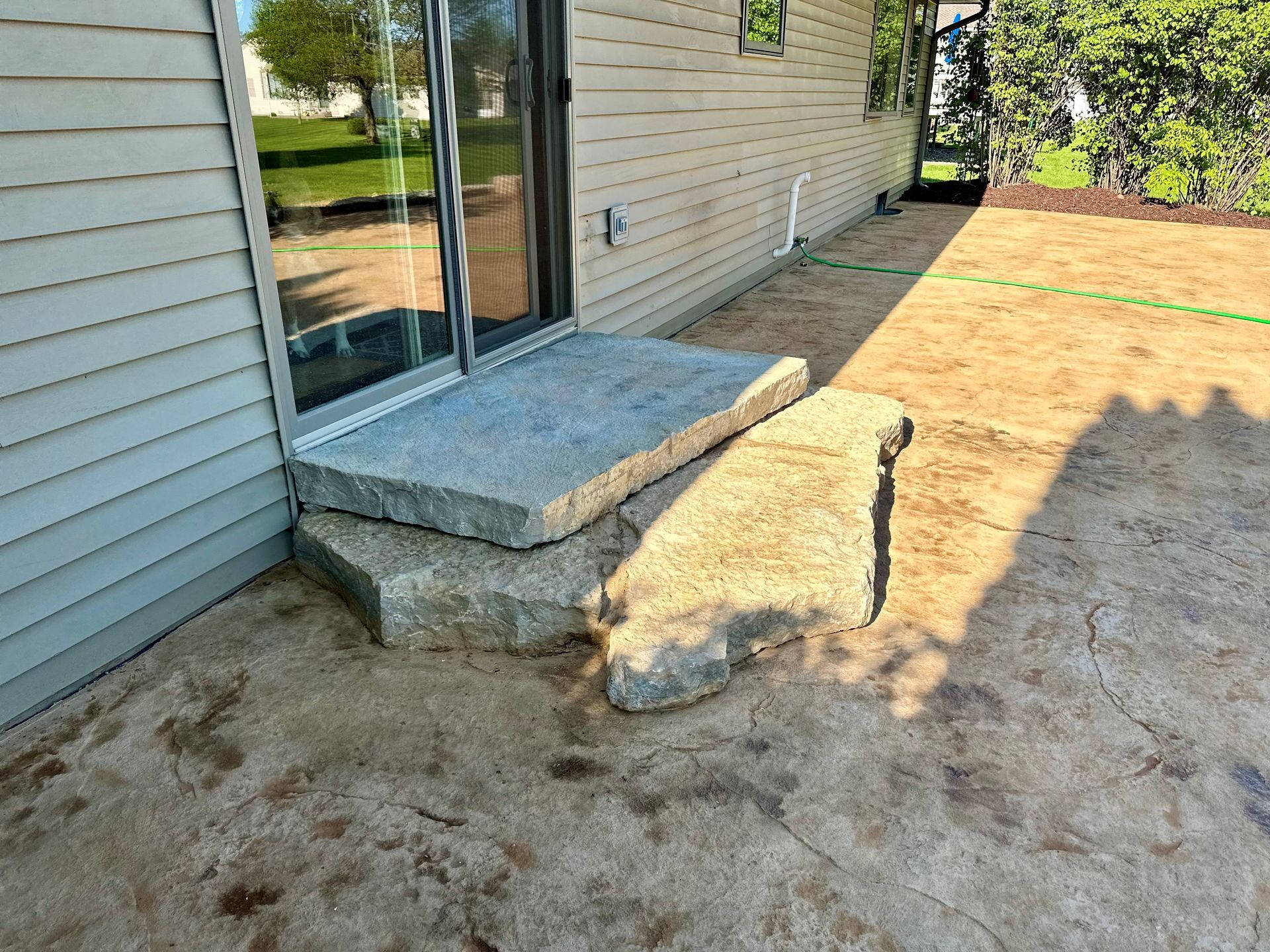 Cut stone slab steps from a sliding patio door onto a fresh stamped concrete patio
